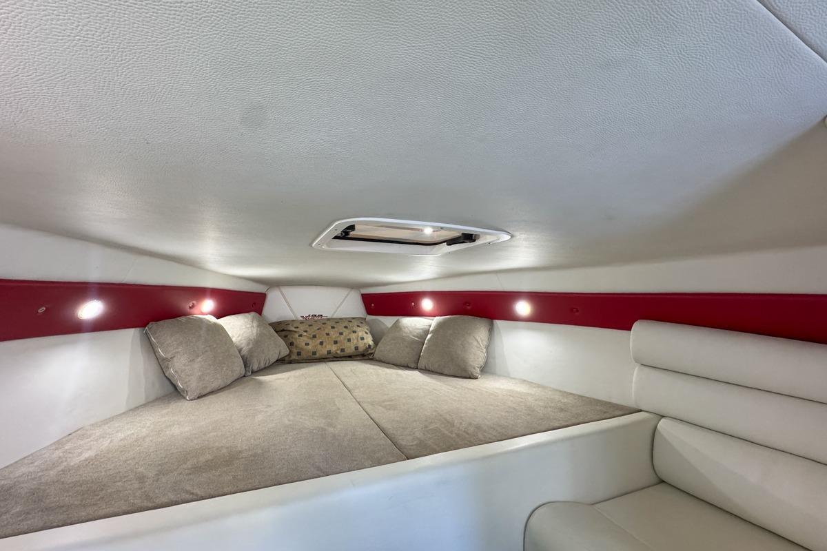 Cozy interior cabin of 2022 Velocity 290sc boat with cushions and ambient lighting.