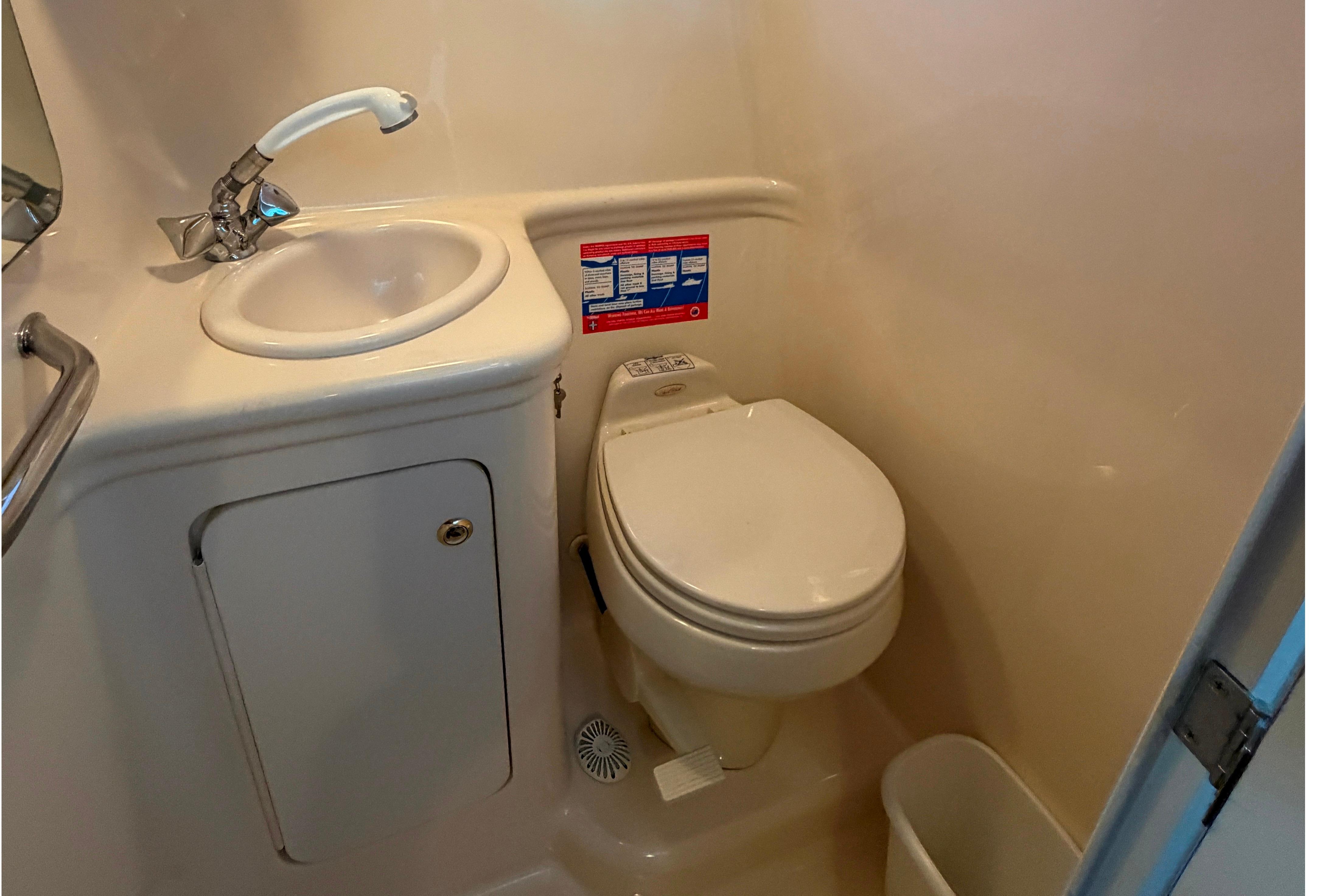 Compact bathroom in 2004 Sea Ray Sundancer 260 boat with sink and toilet.