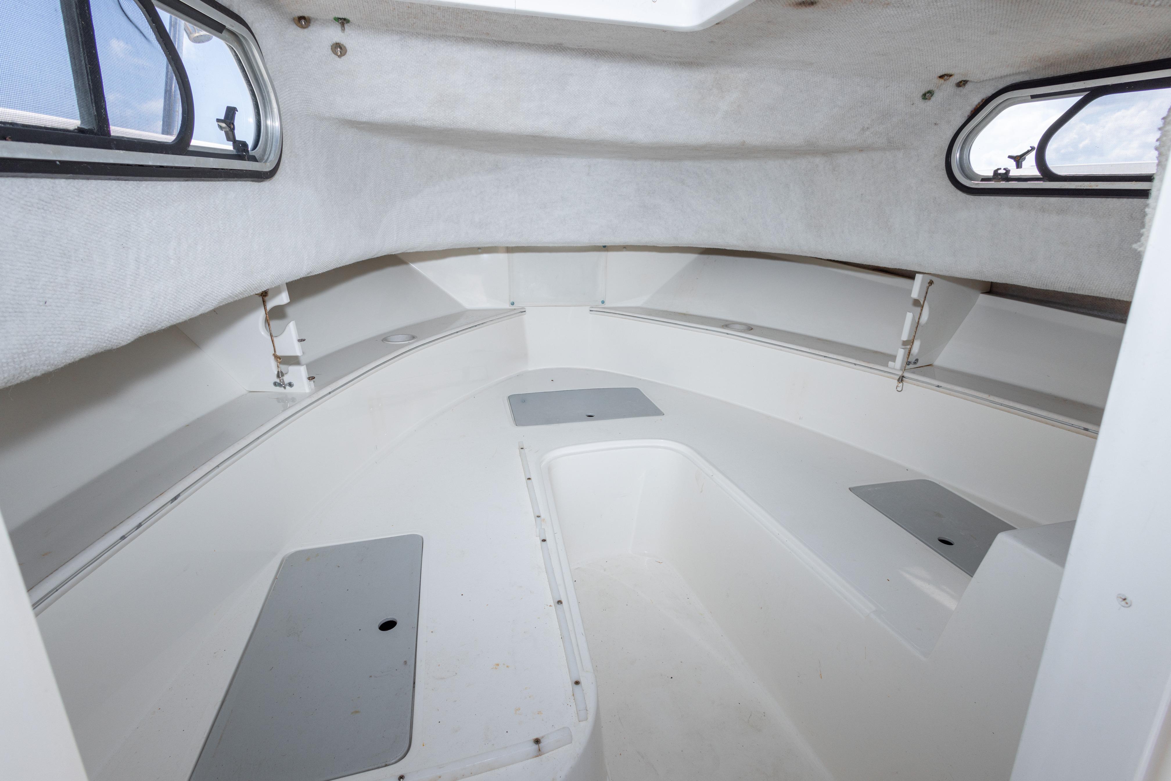 Interior cabin of 1999 Aquasport 225 Explorer boat, featuring white seating and windows.