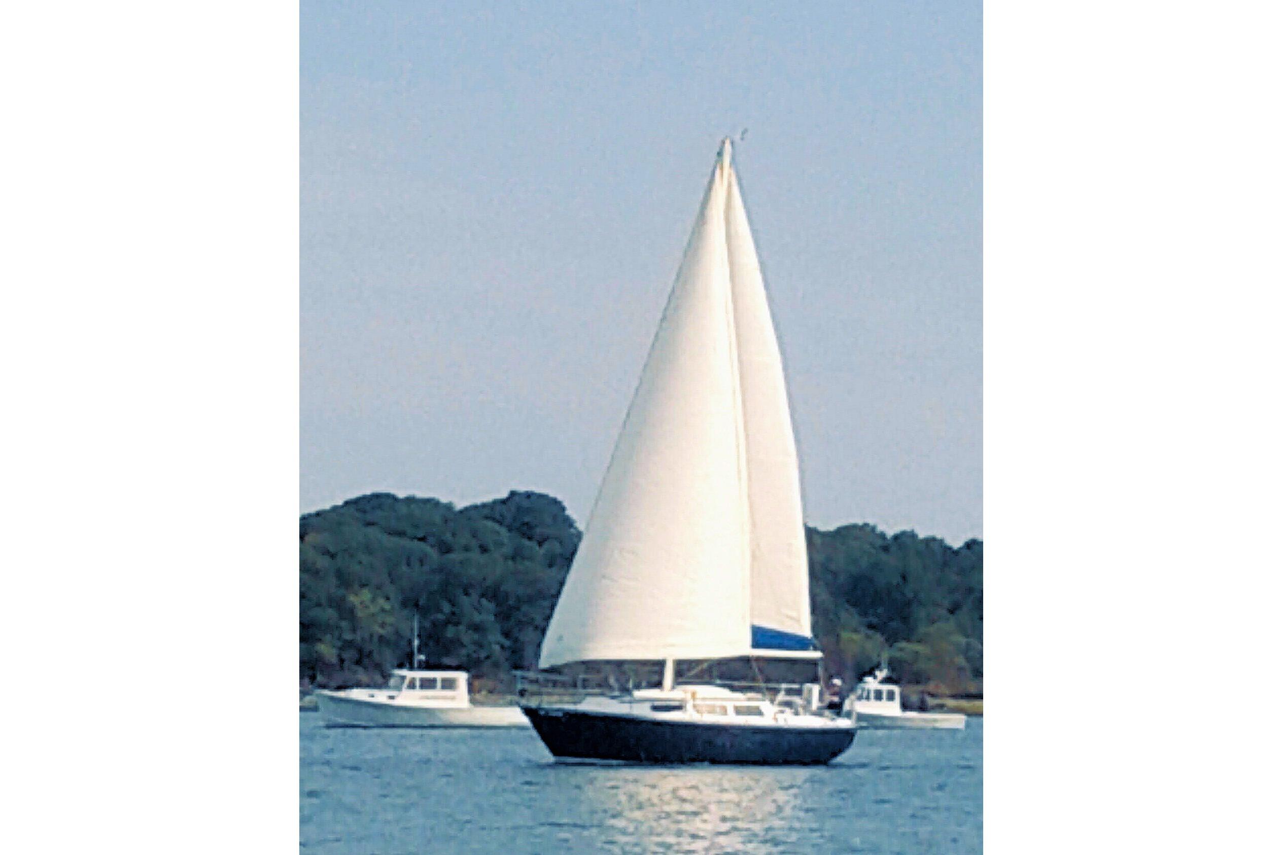 1981 S2 9.2A sailboat on calm water with trees in the background.
