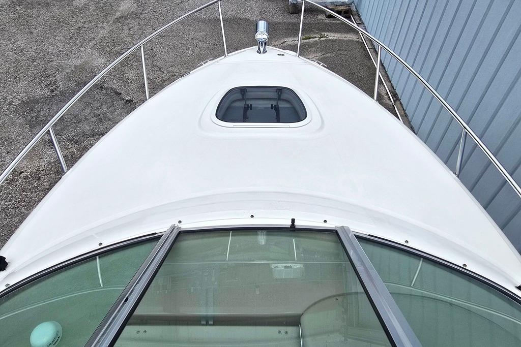 2006 Sea Ray 240 Sundancer boat deck with hatch and railing, docked beside a building.