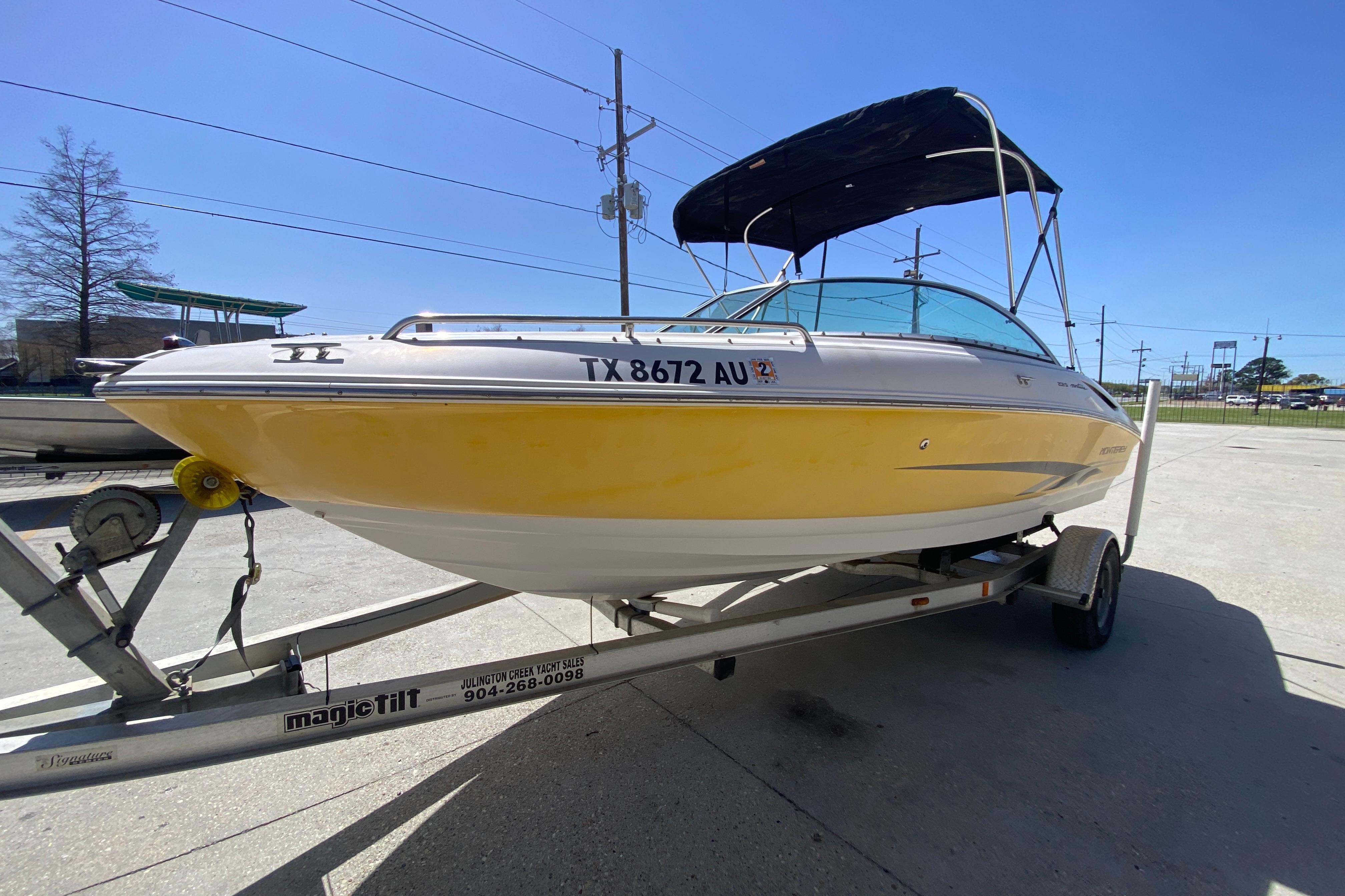 2003 Monterey 208SI Montura boat on trailer, yellow hull, parked outdoors.