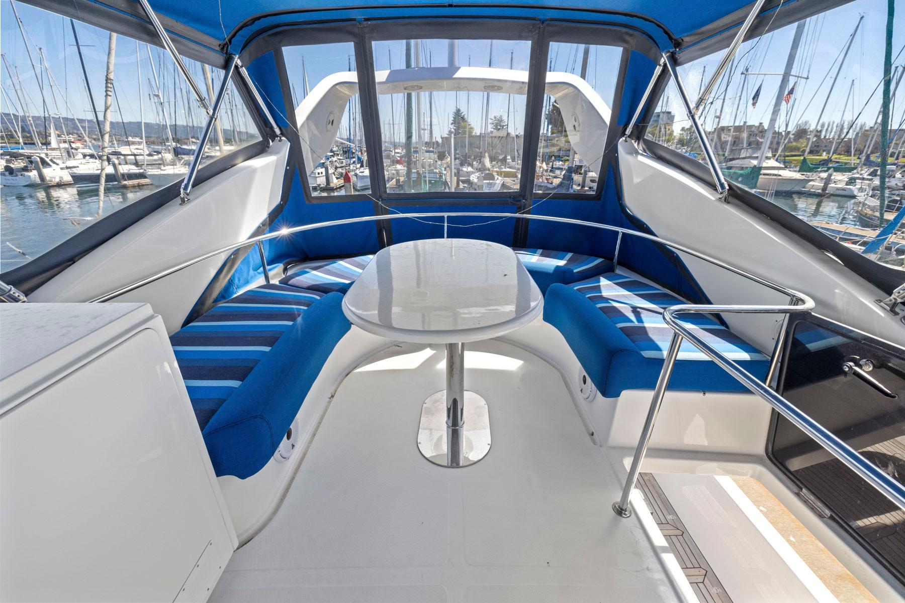 2008 Dyna 51 yacht interior with blue seating and table, docked at marina.