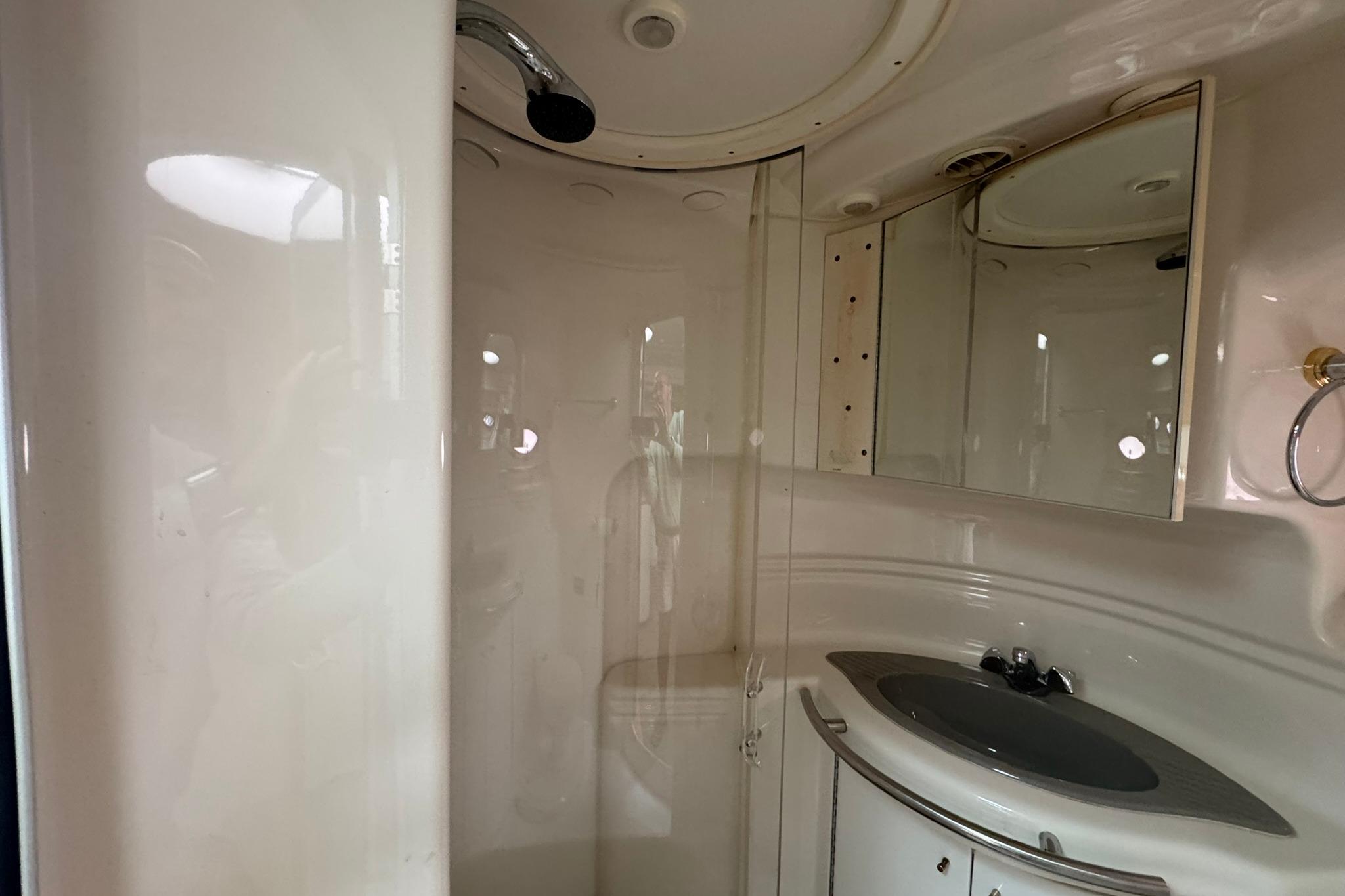 1998 Maxum 3700 SCR yacht bathroom with shower, sink, and mirrored cabinet.