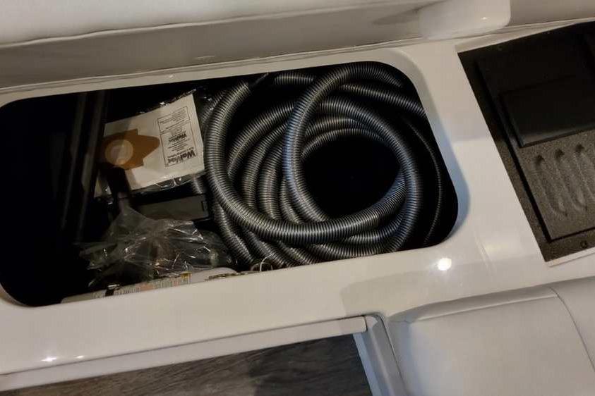Storage compartment in 2023 Formula 380 Super Sport Crossover OB with coiled hose and accessories.