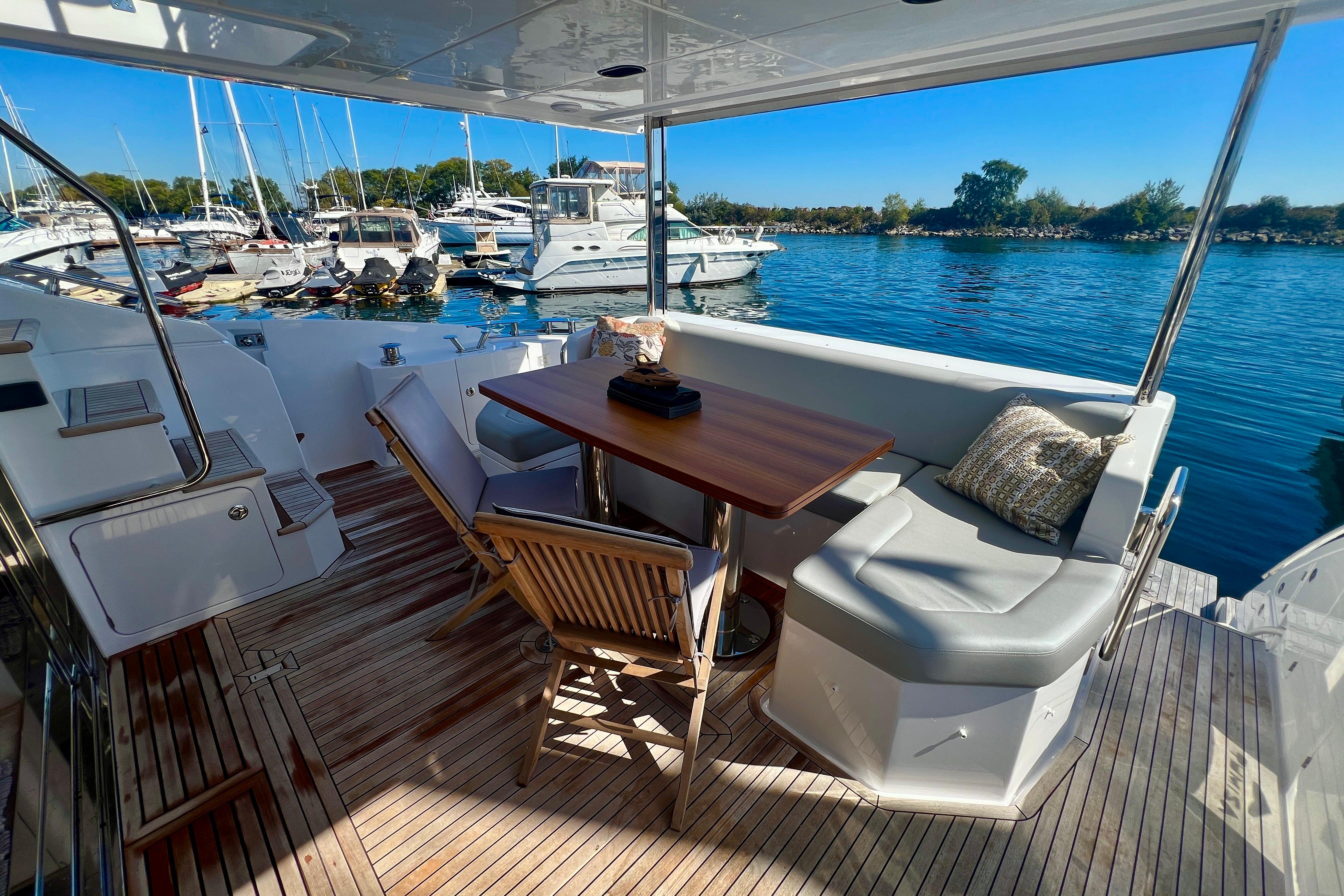 Luxurious 2024 Azimut Fly 60 yacht deck with seating, table, and marina view.
