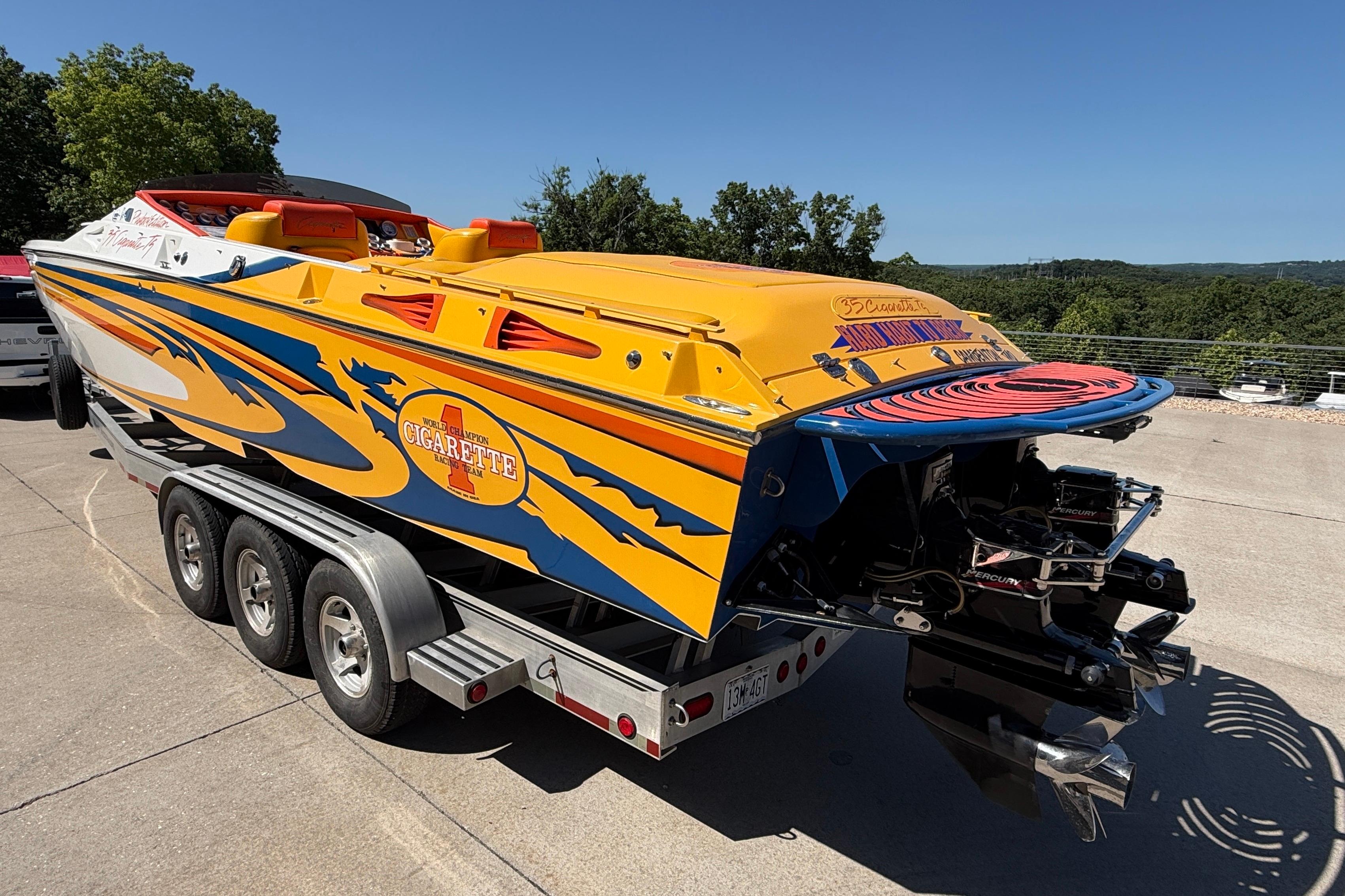 2002 Cigarette 35' Cafe Racer boat on trailer, vibrant yellow and blue design.