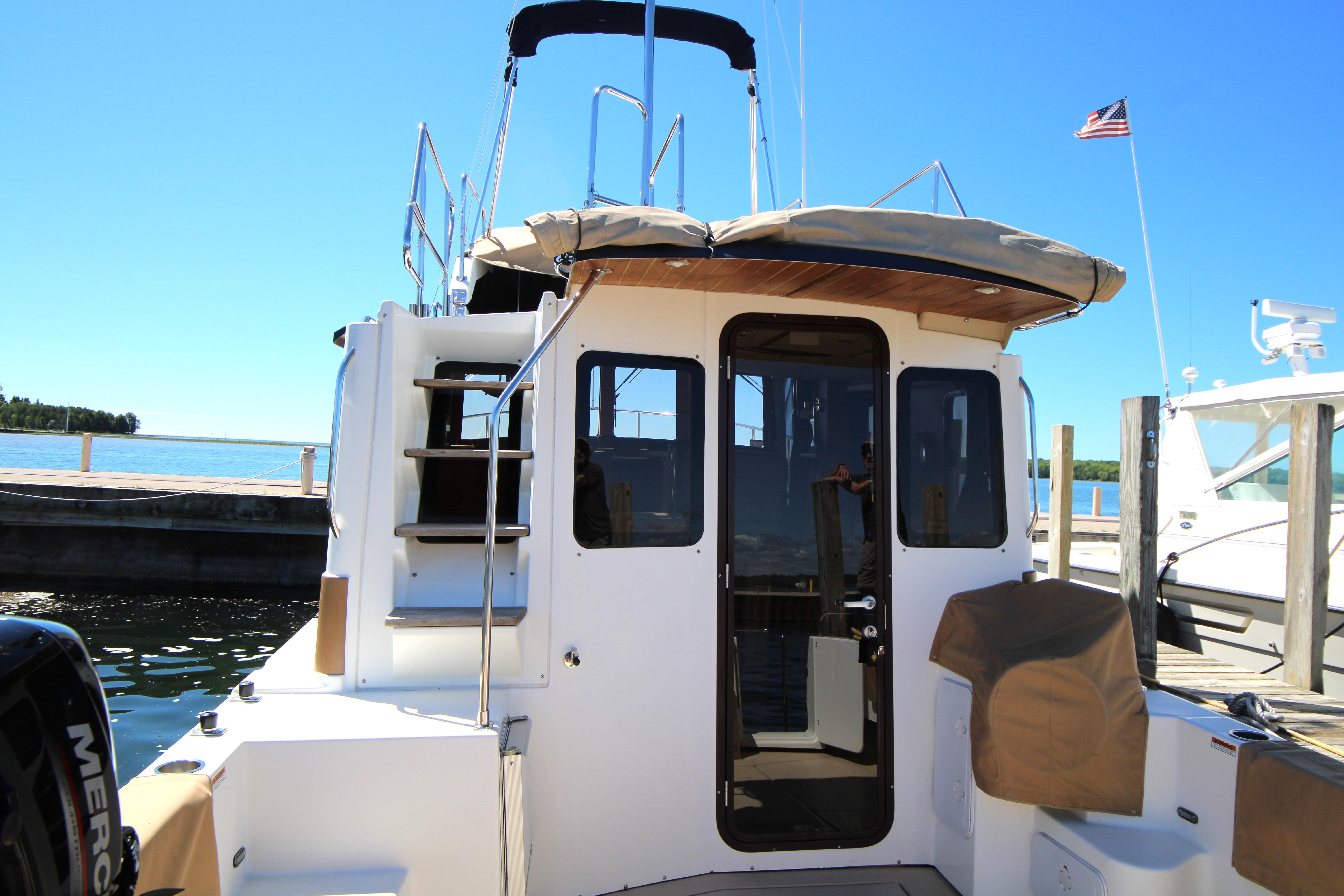 2013 Ranger Tugs R-31 CB docked, rear view with stairs and American flag.