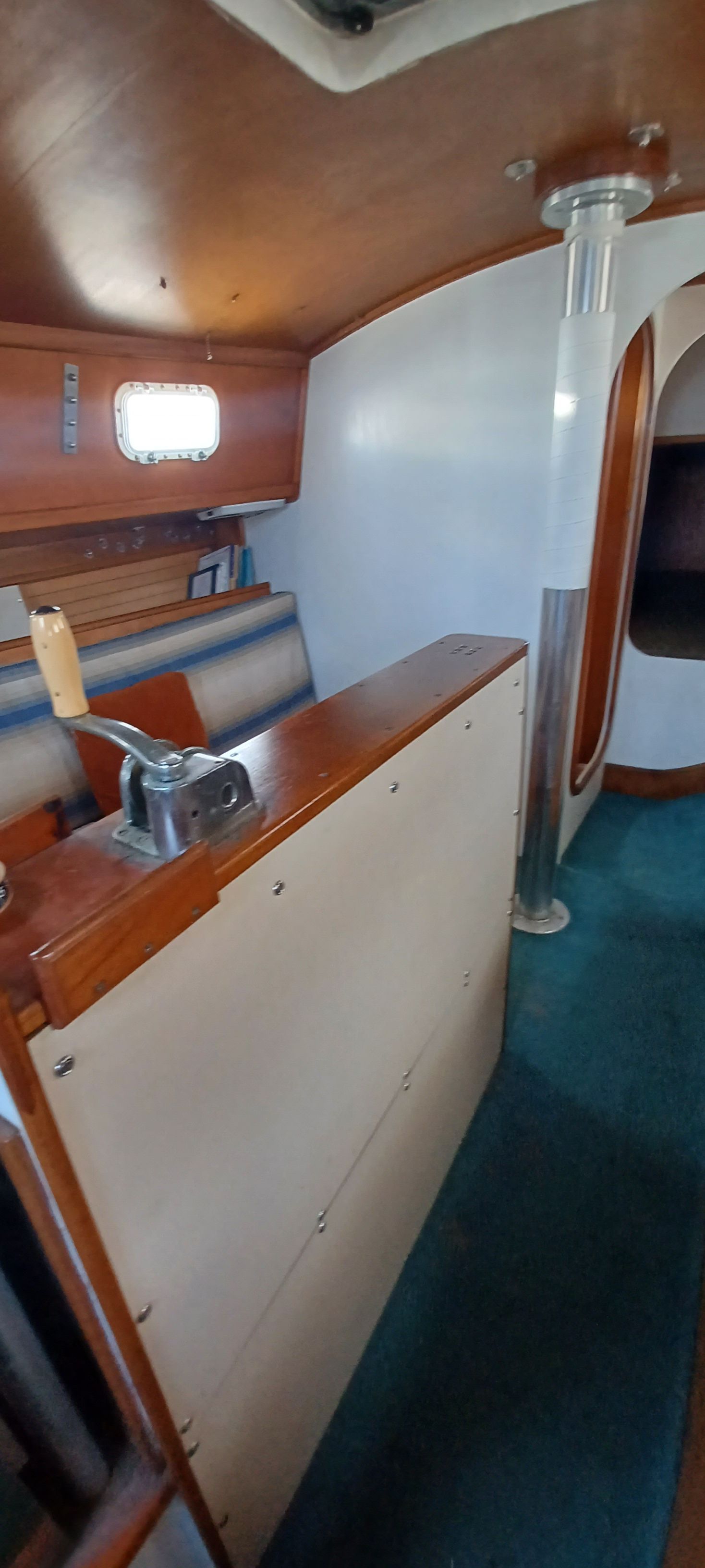 Interior of a boat with wooden furnishings and blue carpet.