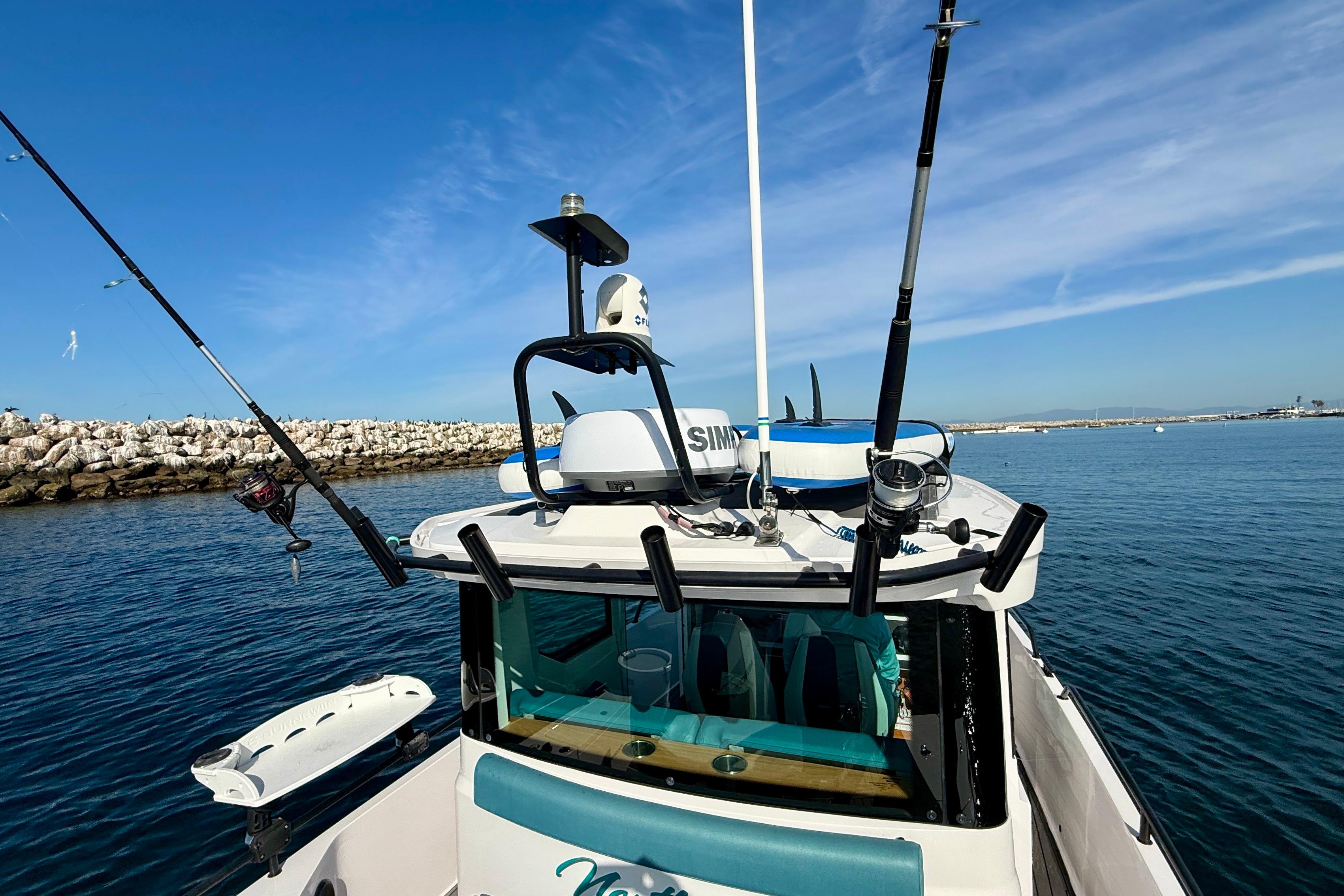 2021 Axopar Brabus 28 Cabin boat with fishing rods, navigating calm waters.