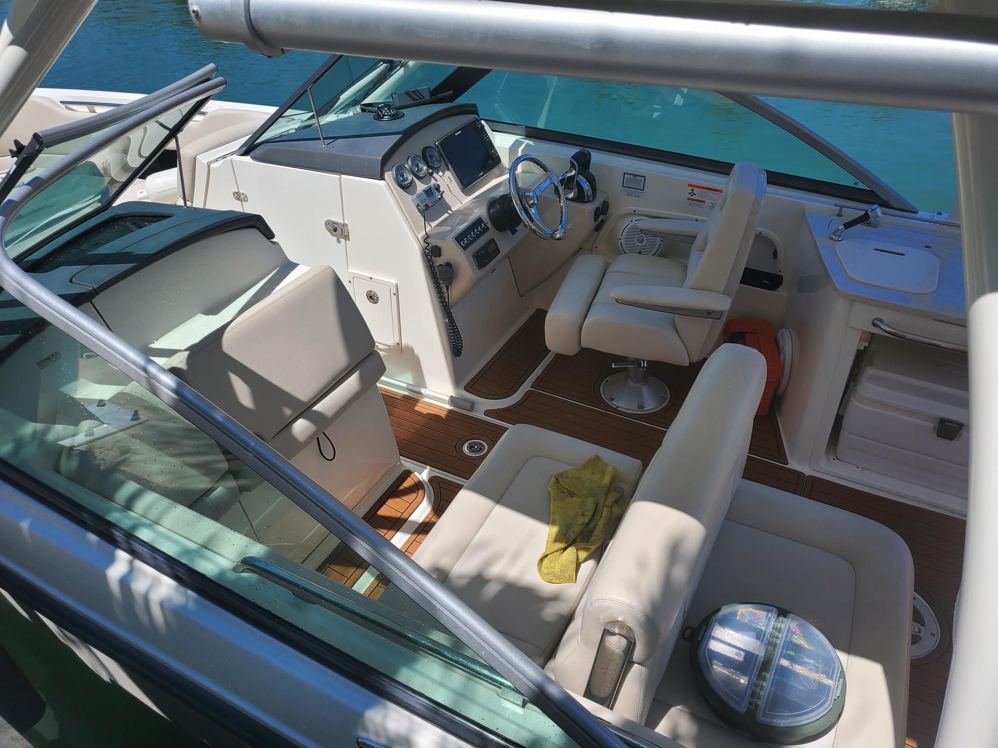 The cockpit of a Boston Whaler 270 Vantage with beige seats and a steering wheel.