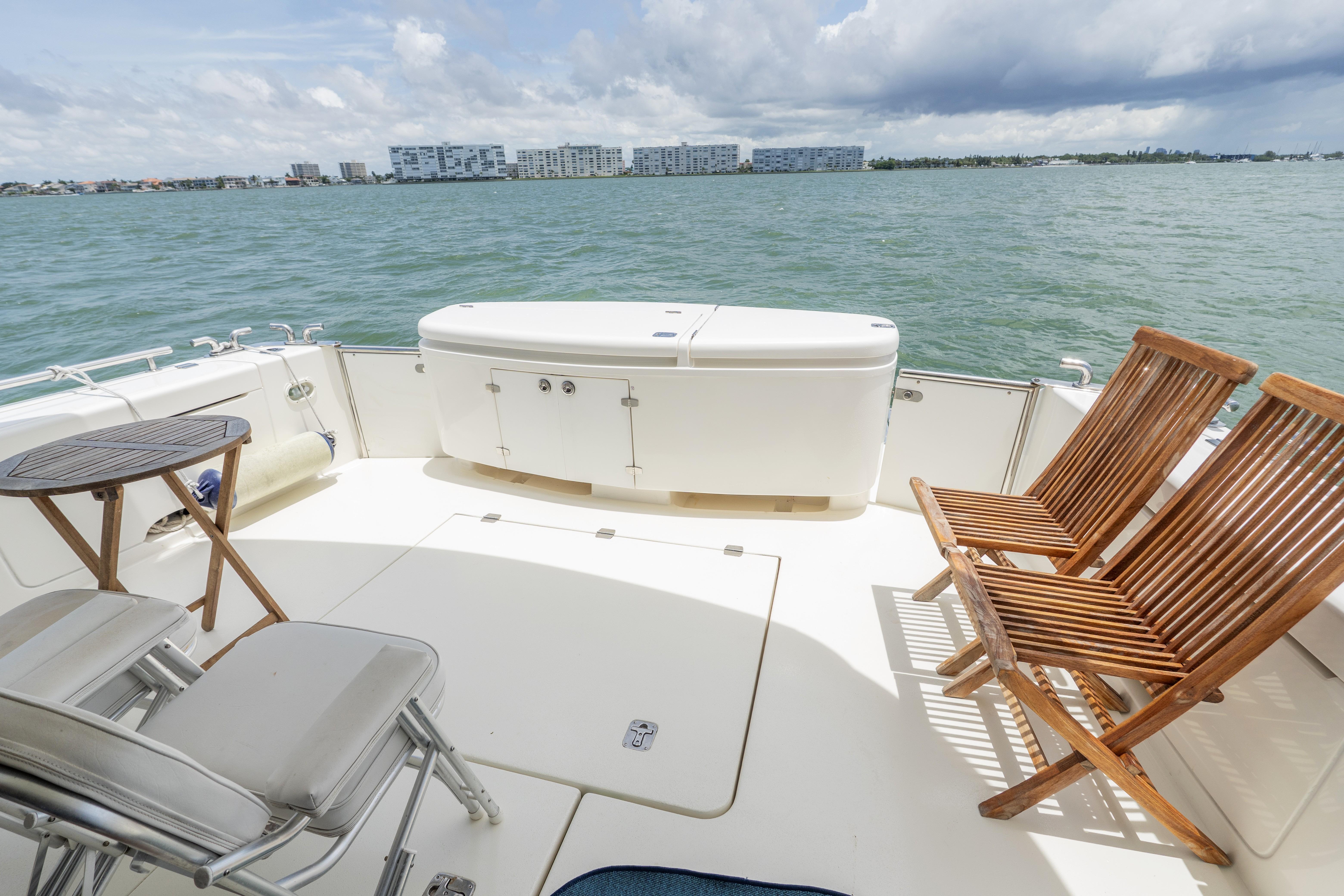 2008 Maritimo 52 yacht deck with wooden chairs, table, and ocean view.