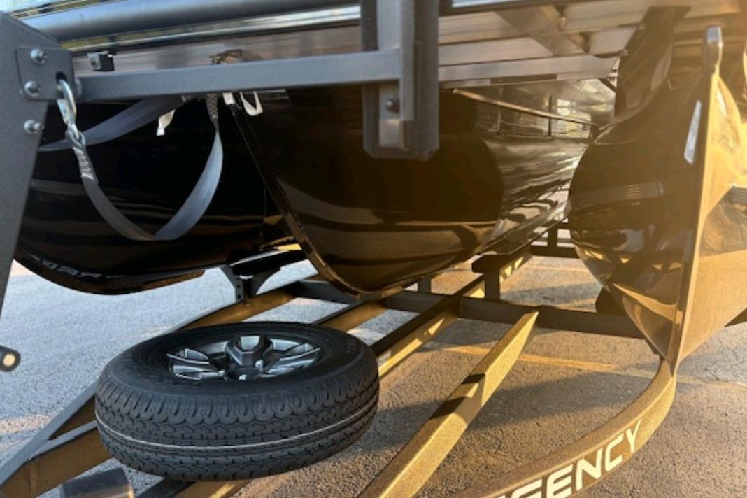 Underneath view of a 2026 Regency 230 DL boat on a trailer with spare tire.