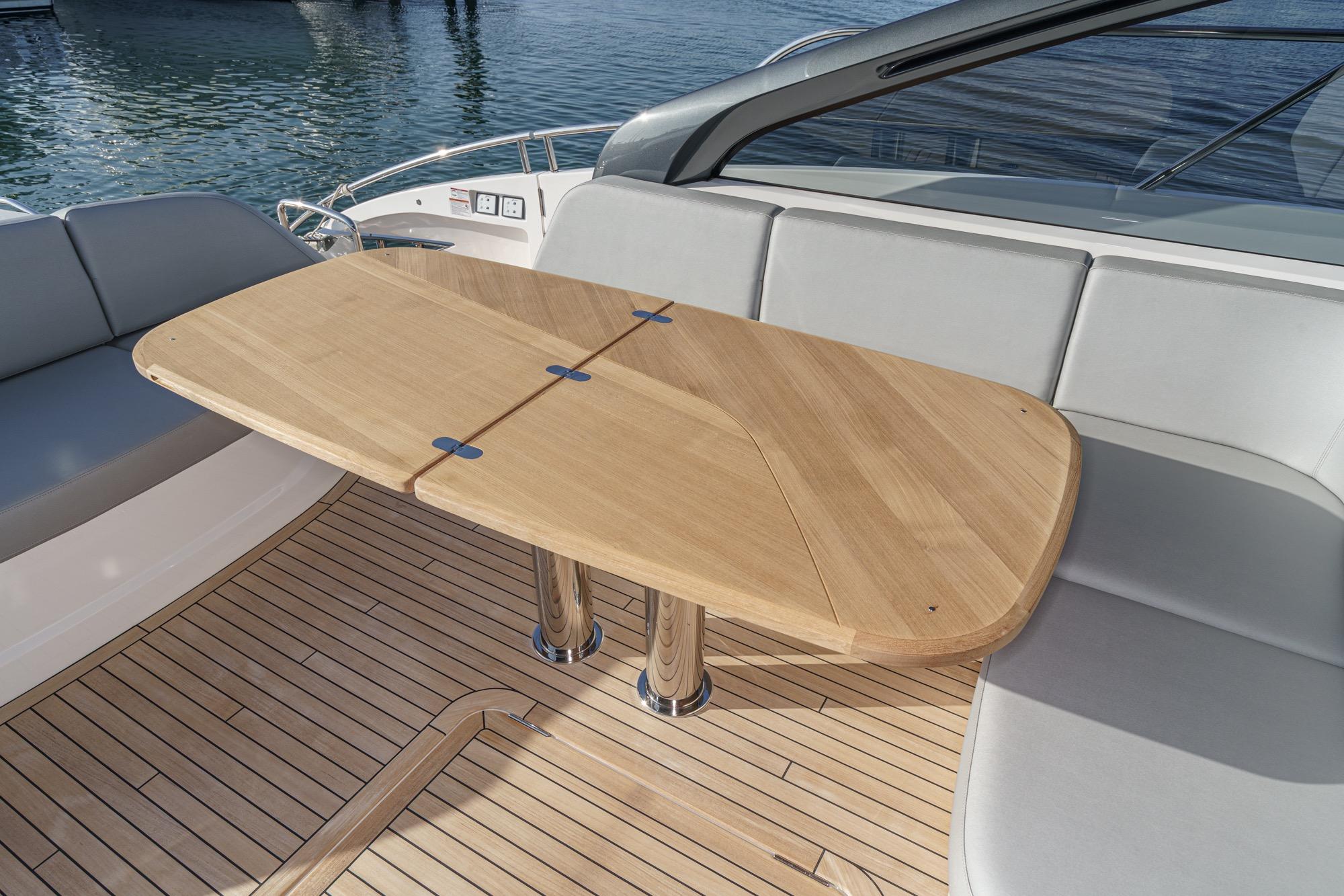 Luxury seating area on 2026 Princess V55 yacht with wooden table and cushioned seats.