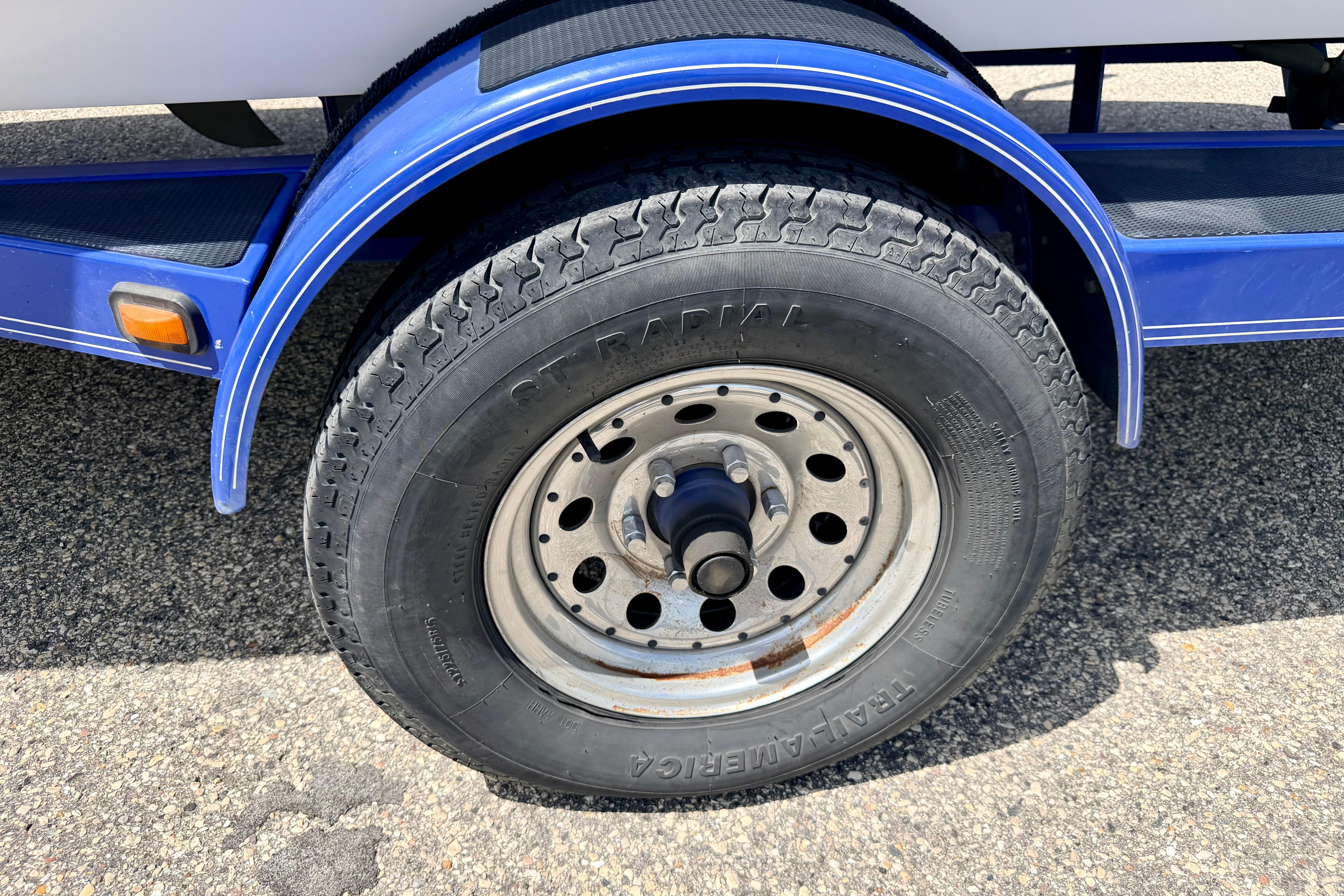 2008 Moomba Outback V trailer wheel with blue fender on asphalt surface.