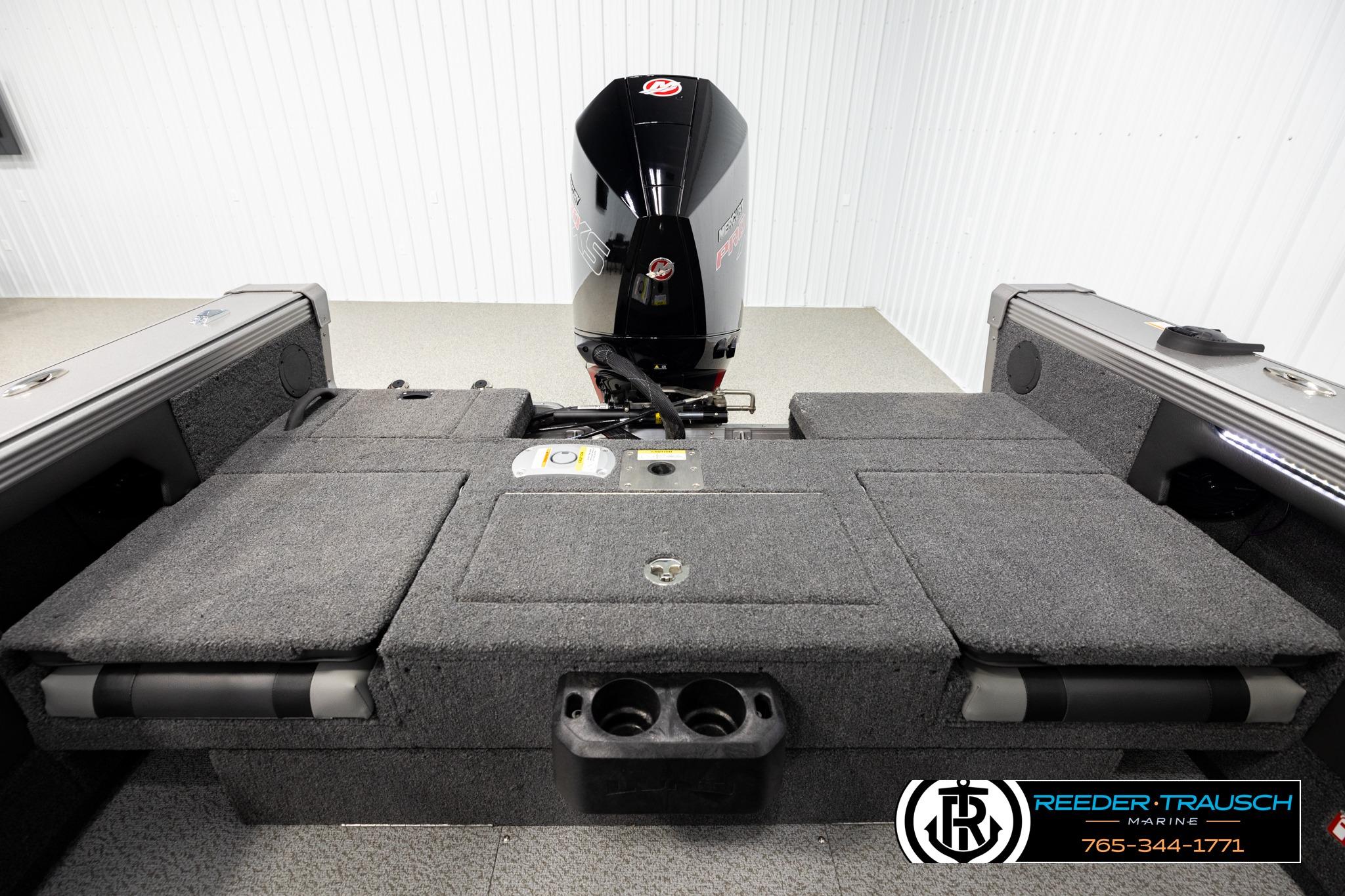 2026 Lund 1975 Tyee boat interior with motor, featuring carpeted deck and storage compartments.