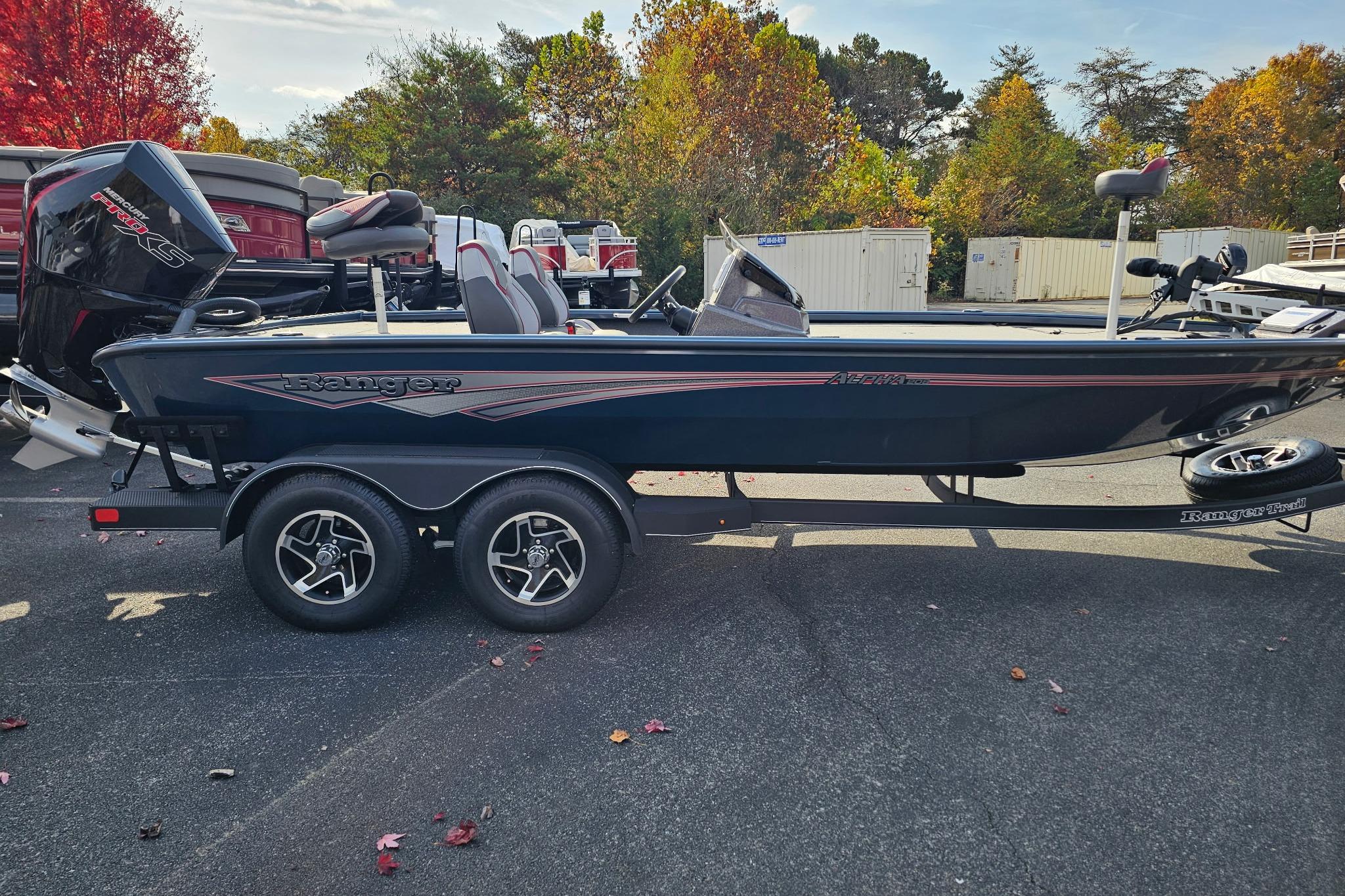 2025 Ranger ALPHA 208 boat on trailer, parked outdoors with autumn foliage background.