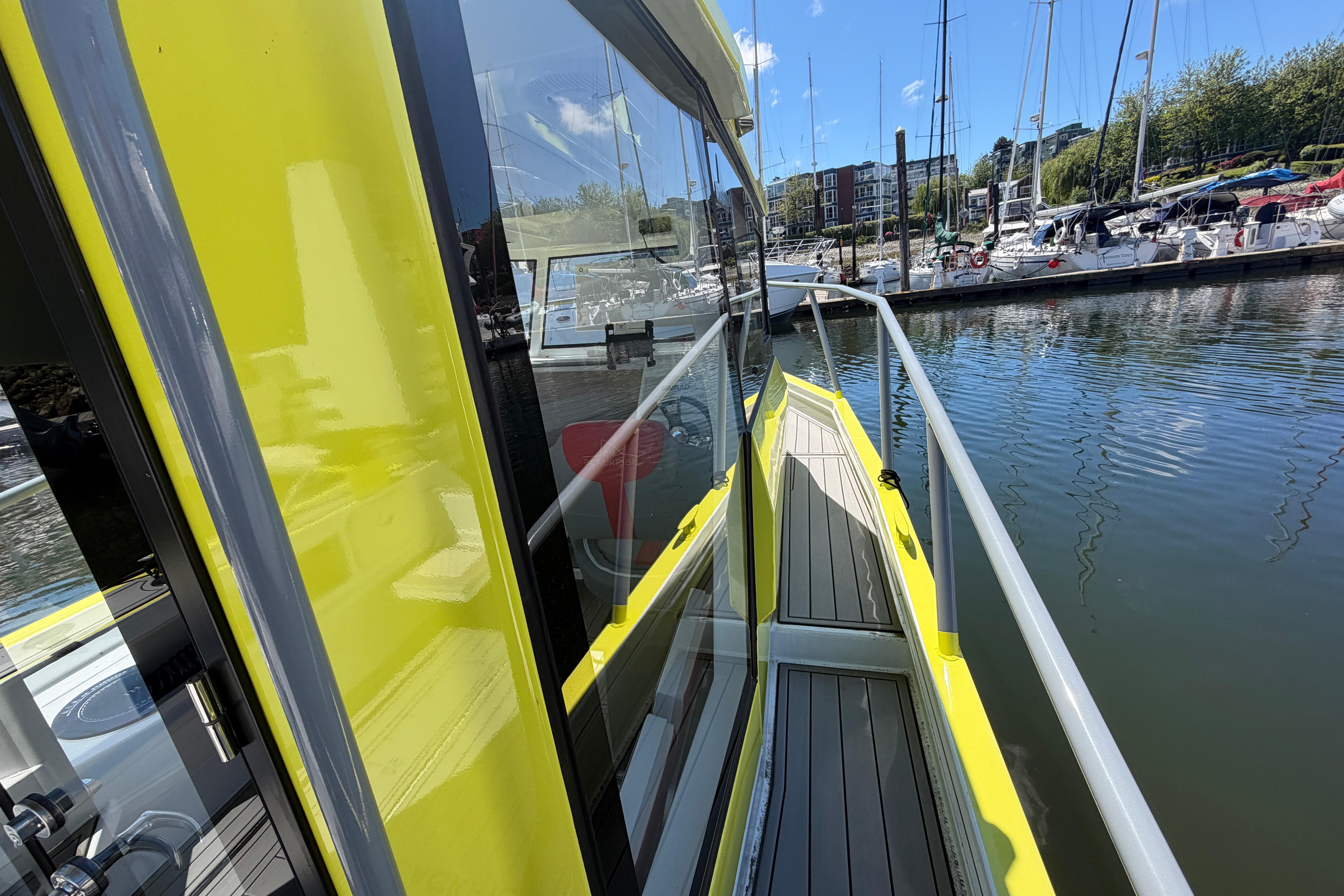 Yellow Blackfish E750w boat docked at marina, reflecting water and surrounding yachts.