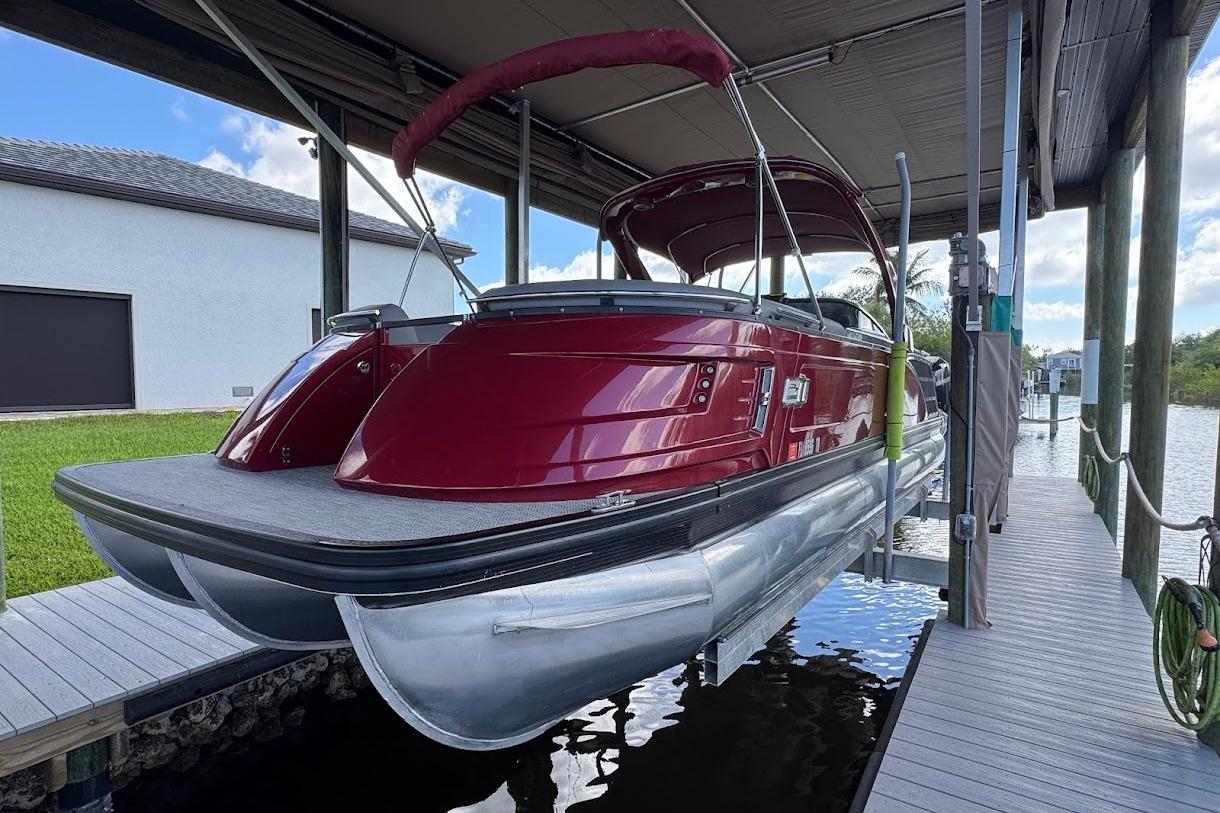 2024 Bennington QX27 pontoon boat docked under a canopy.