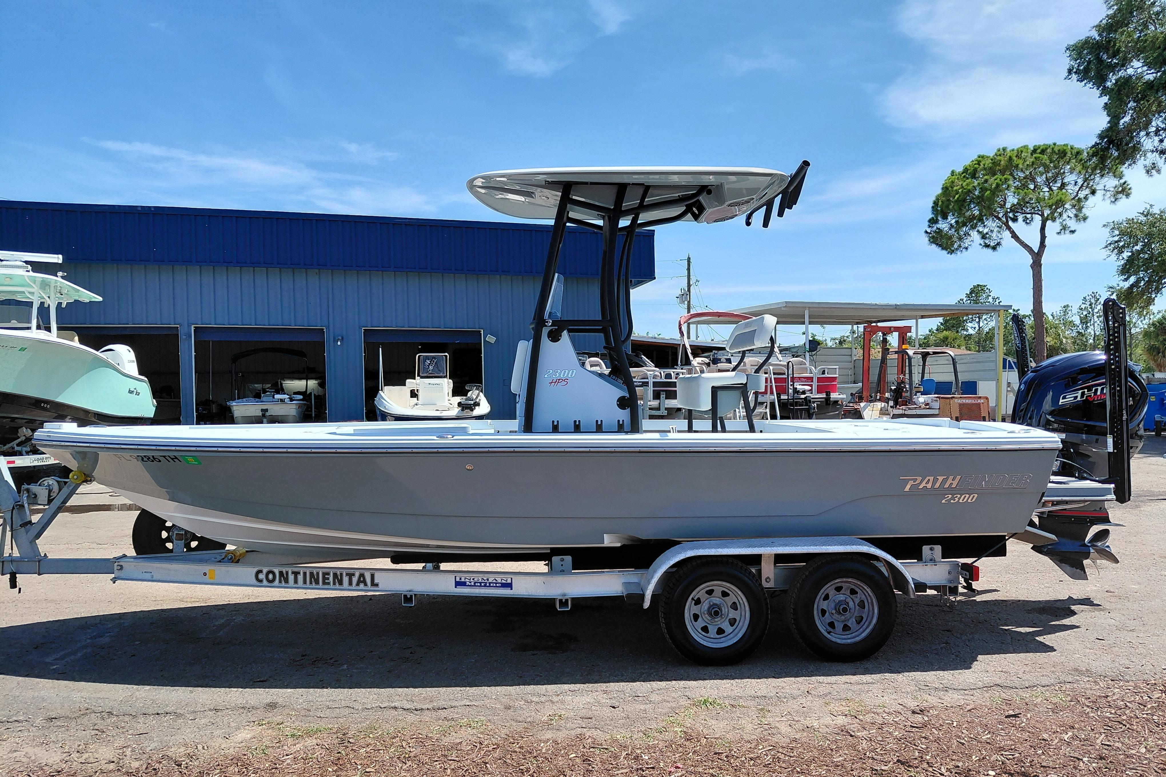 2022 Pathfinder 2300 HPS boat on trailer, parked outdoors near a blue building.