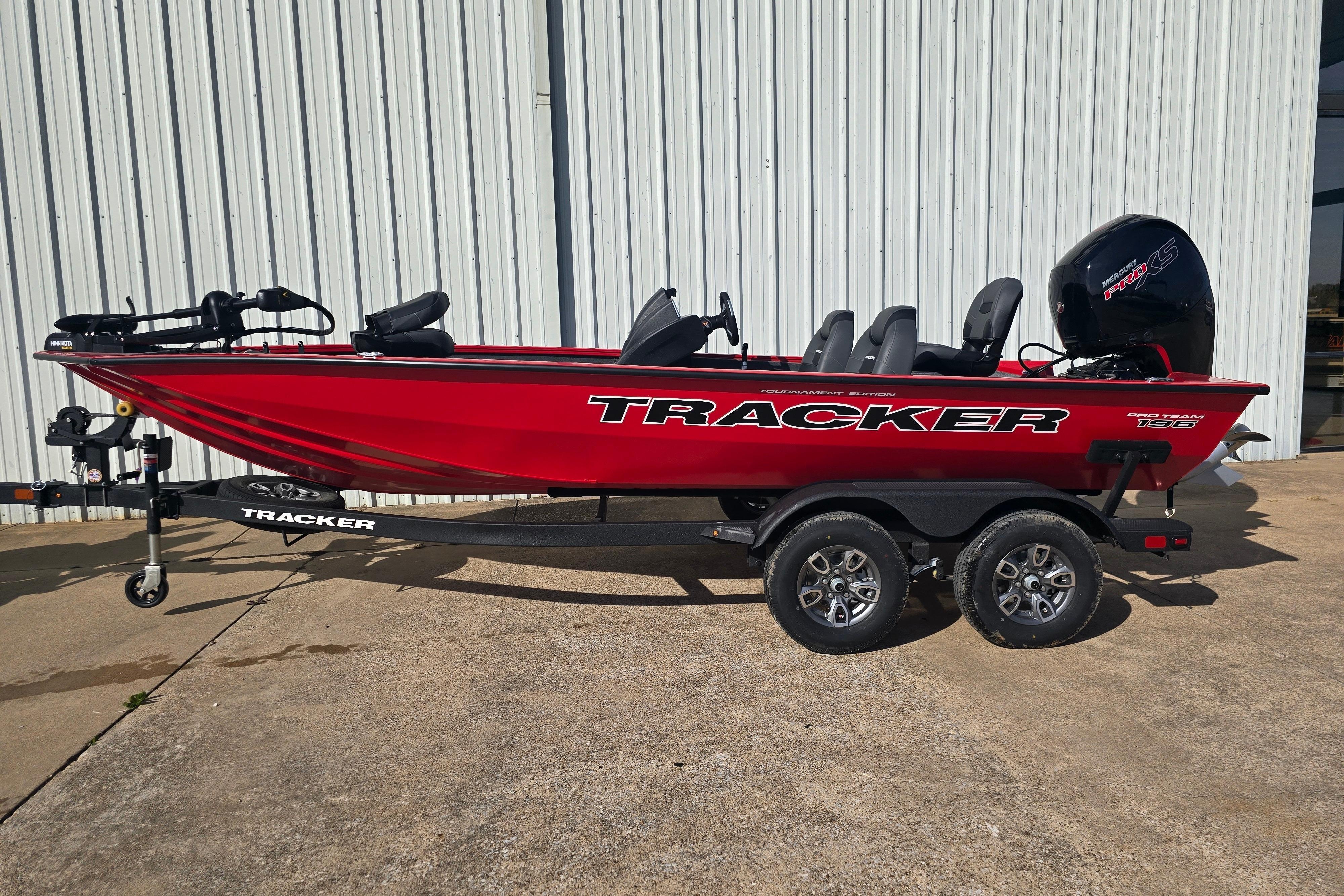 2026 Tracker Pro Team 195 boat, red, on trailer, parked outside a building.