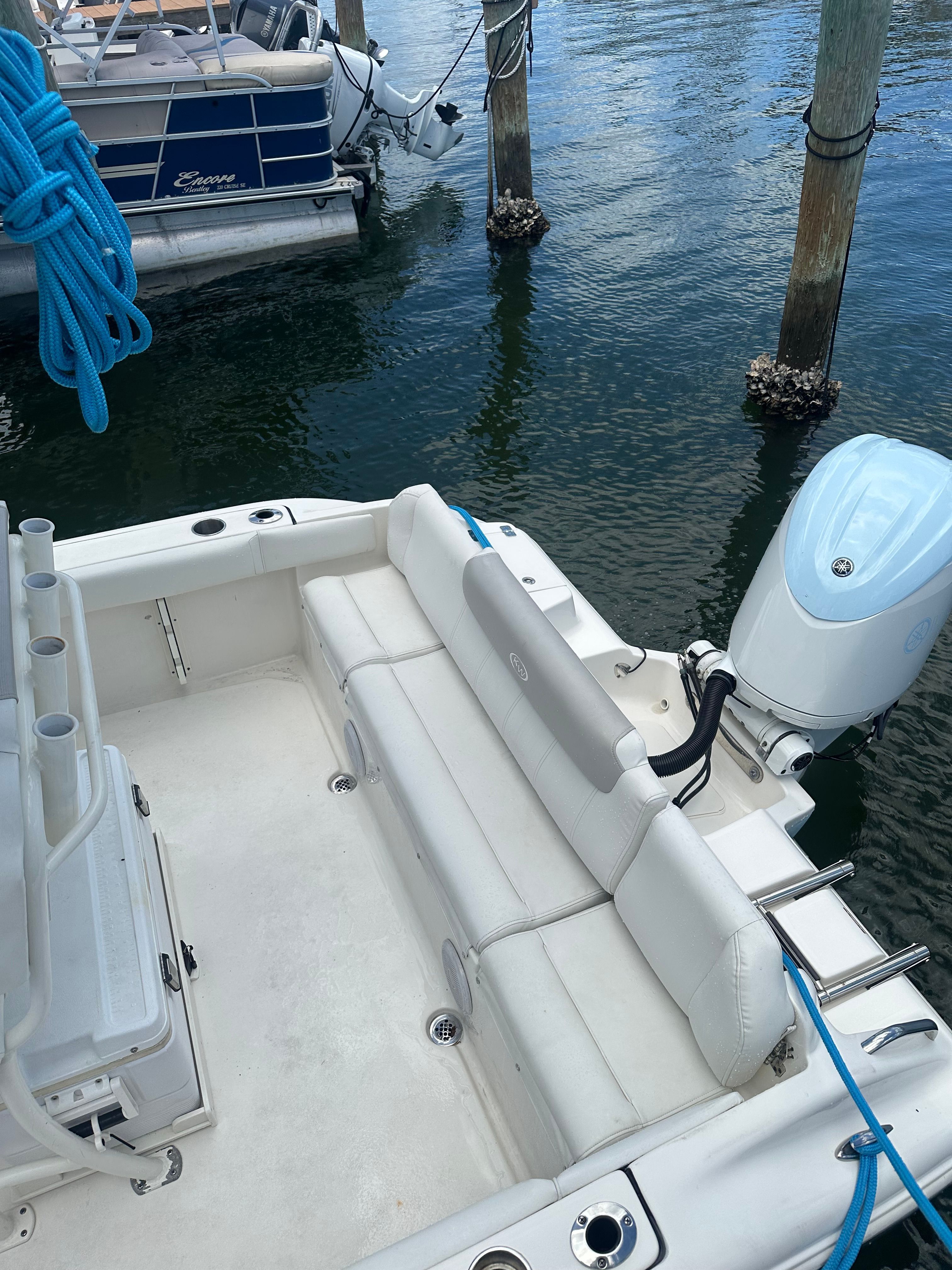 A Key West 219 FS boat is docked in the water. It features white seating and an outboard motor.