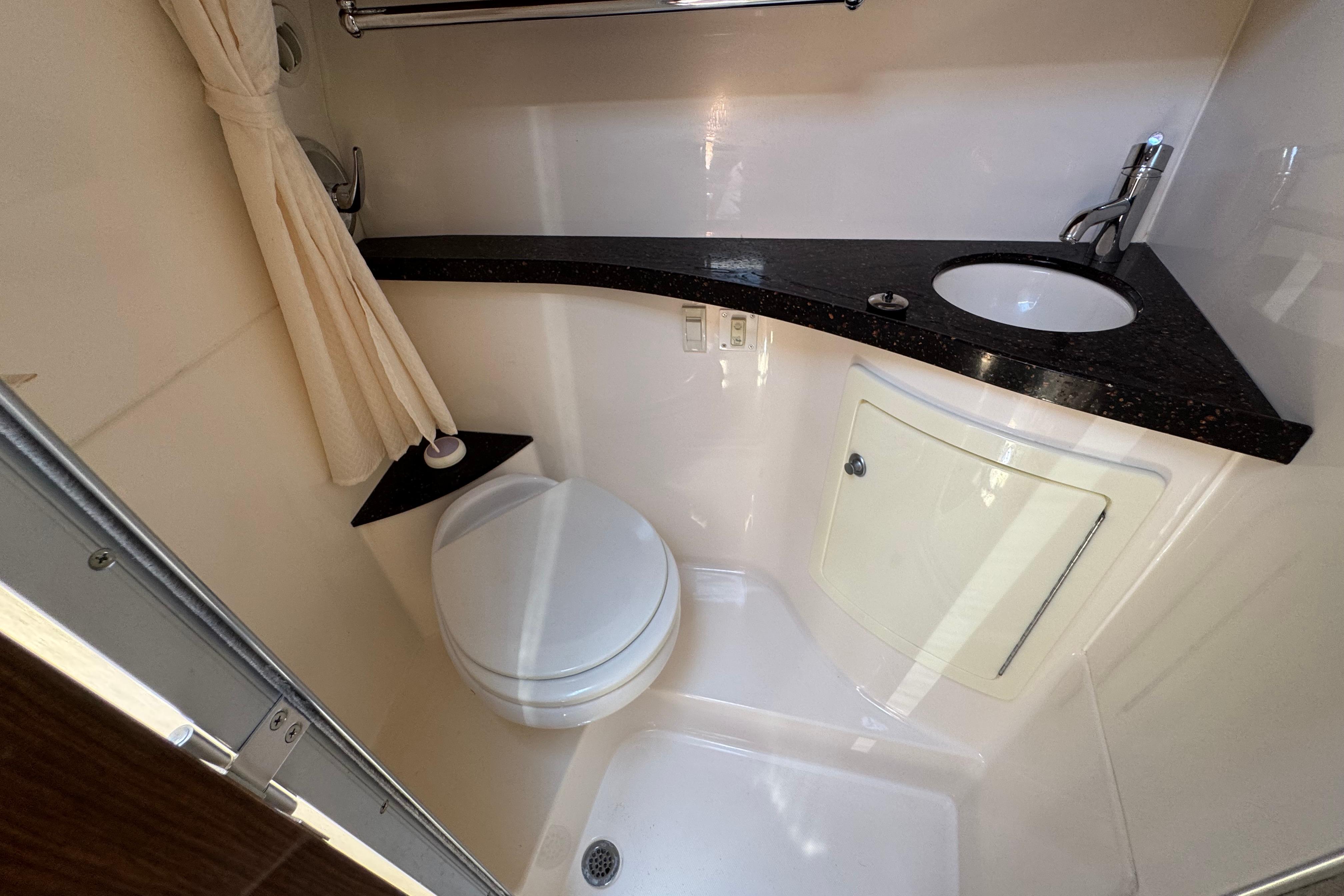 Compact bathroom in a 2013 Regal 28 Express boat with toilet, sink, and shower.