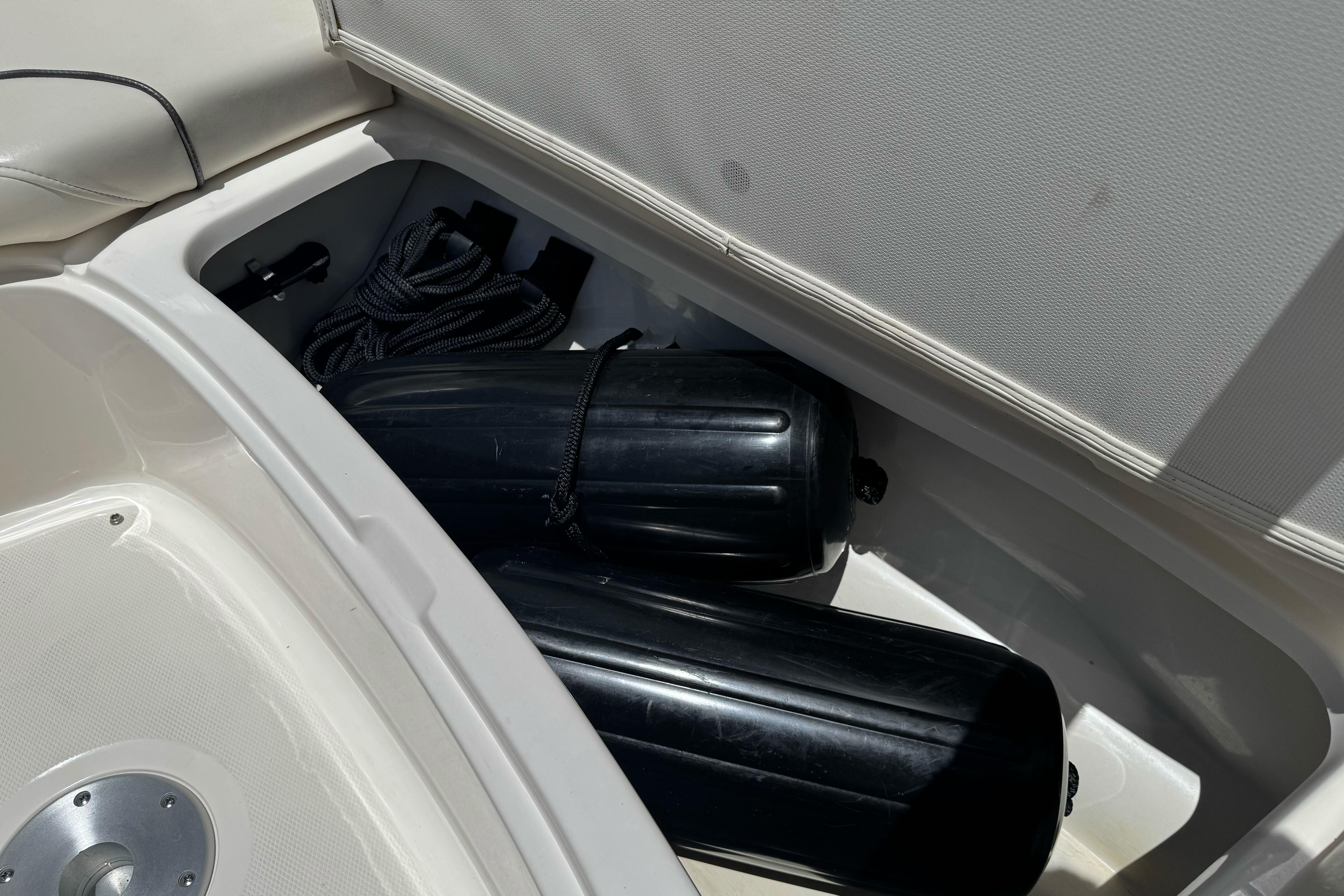 Storage compartment of a 2007 Sea Ray SLX 250 boat with black fenders and rope.