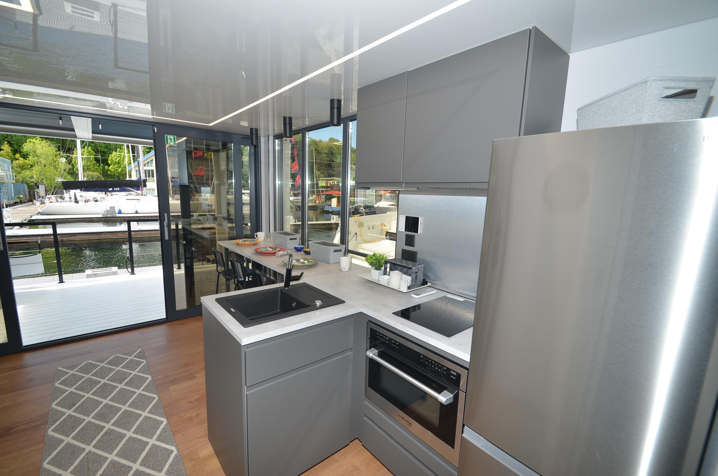 Modern kitchen in La Mare 2024 houseboat, featuring sleek gray cabinetry and stainless steel appliances.