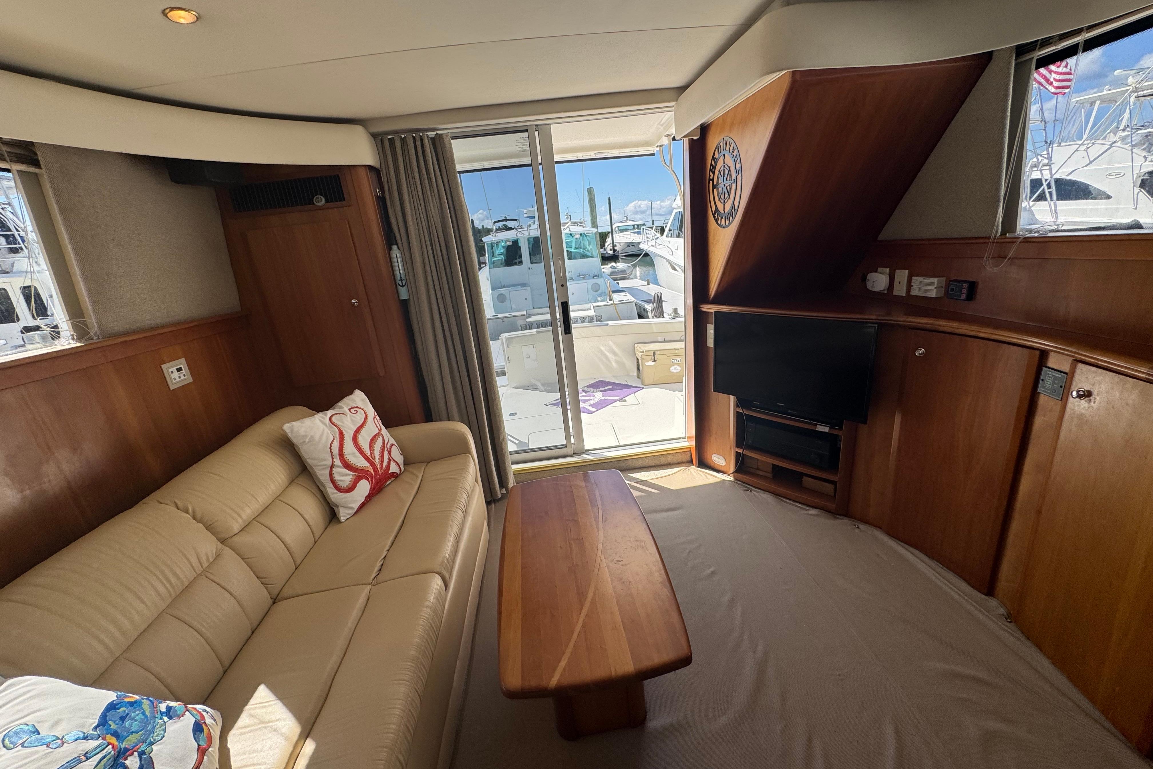Interior of 2003 Silverton 42 Convertible yacht with sofa, TV, and sliding glass door.