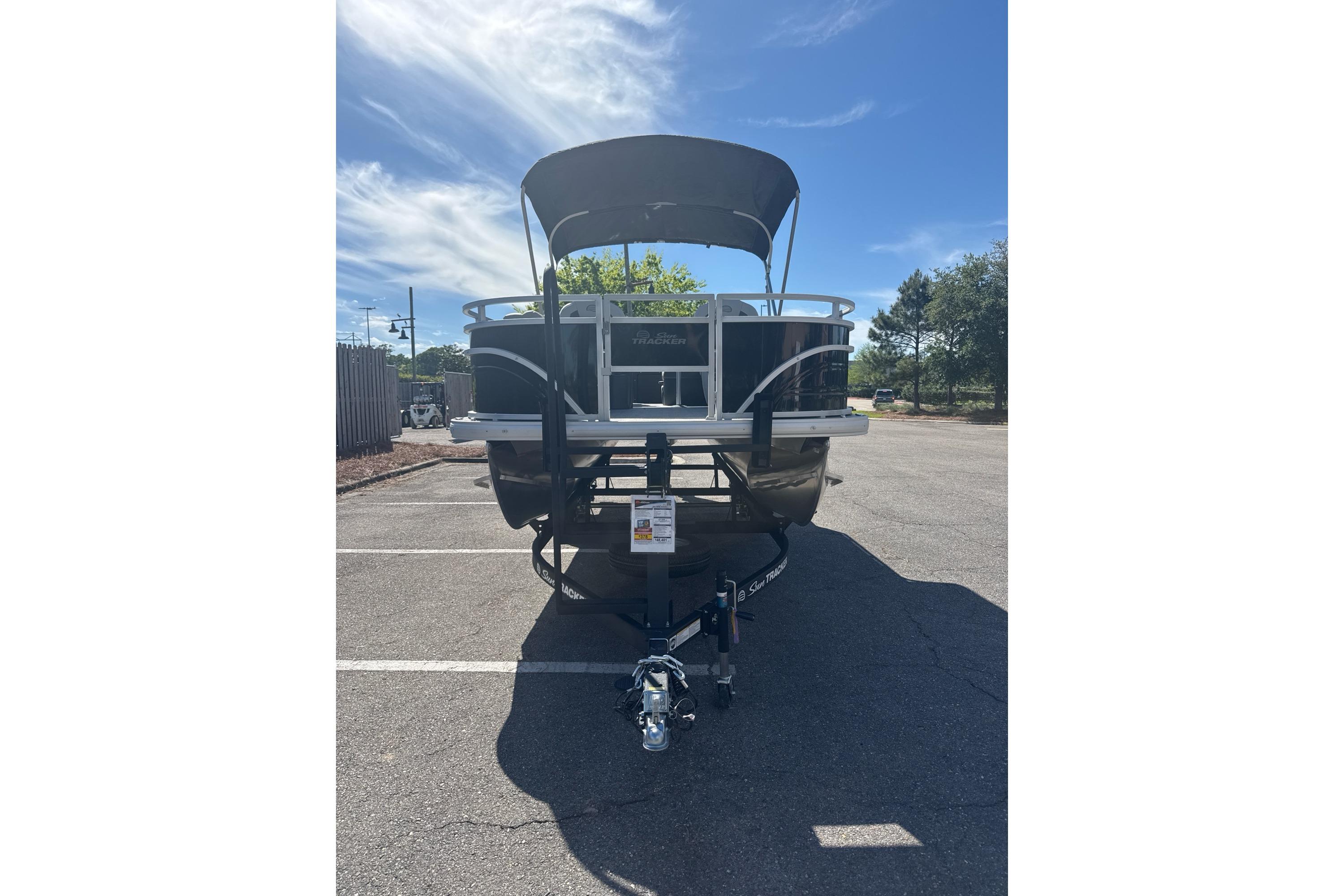 2026 Sun Tracker Fishin' Barge 20 DLX pontoon boat in parking lot, sunny day.
