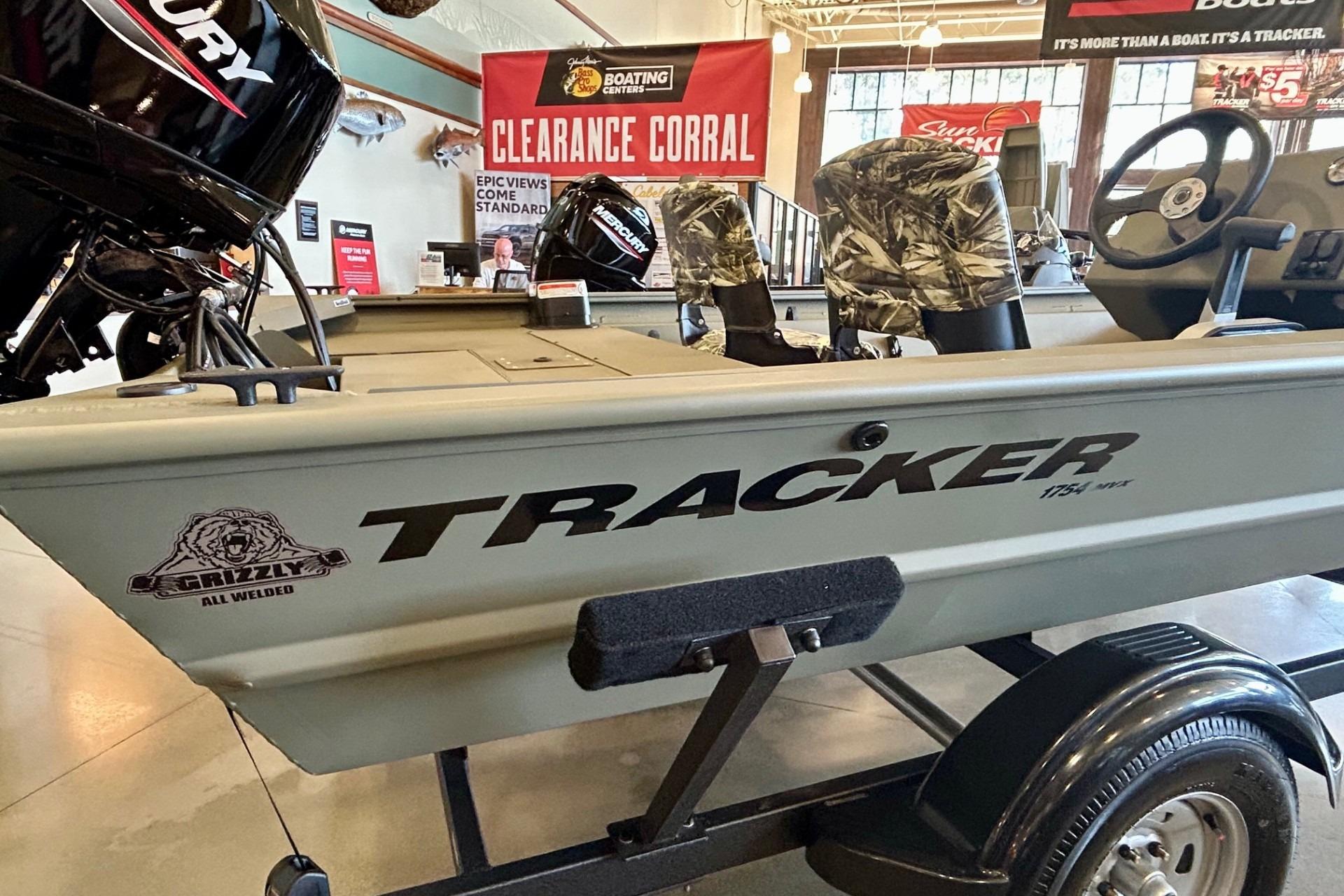 2026 Tracker Grizzly 1754 SC boat on display in showroom with camouflage seats.