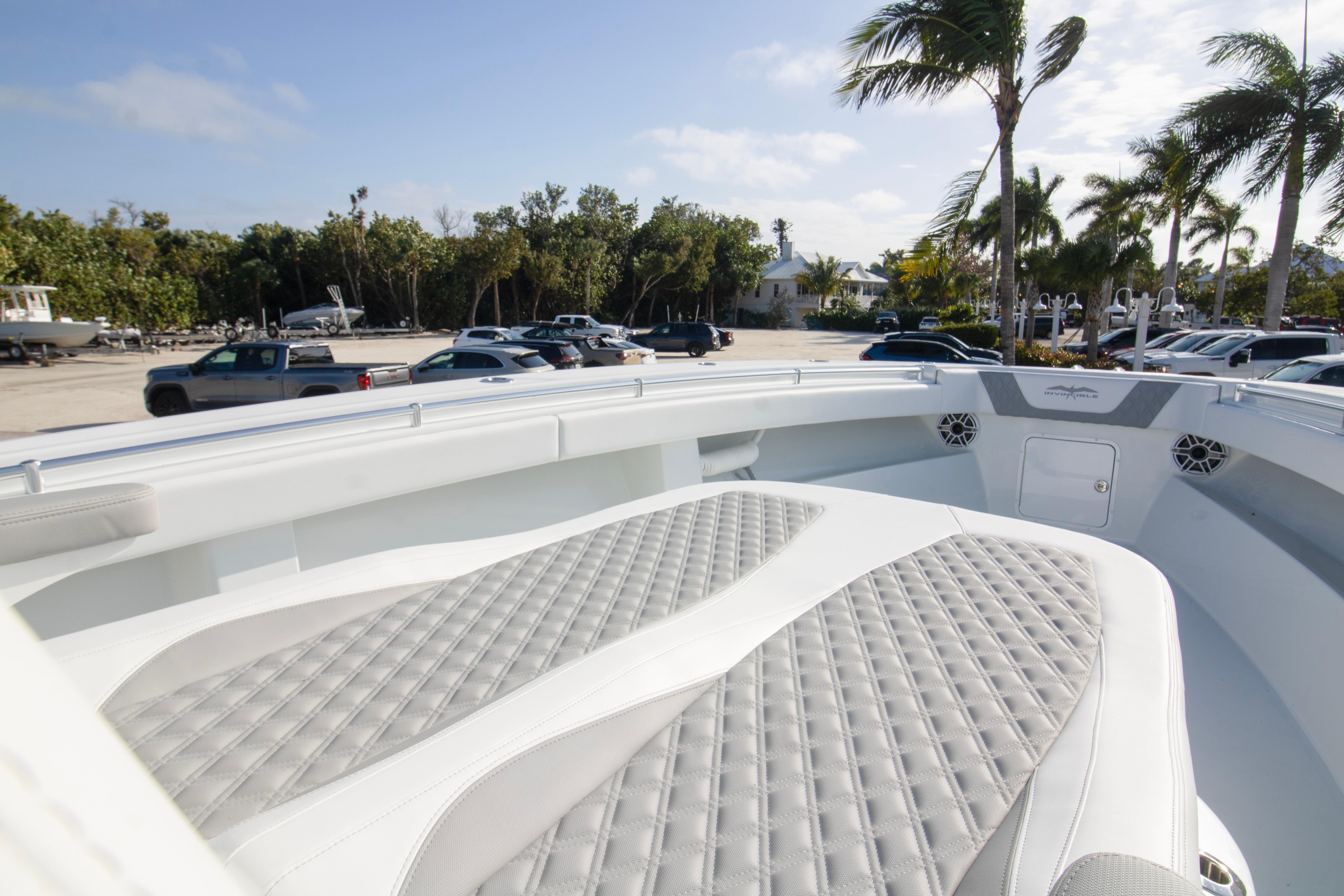 2026 Invincible 39 Open Fisherman boat with cushioned seating, parked near palm trees.