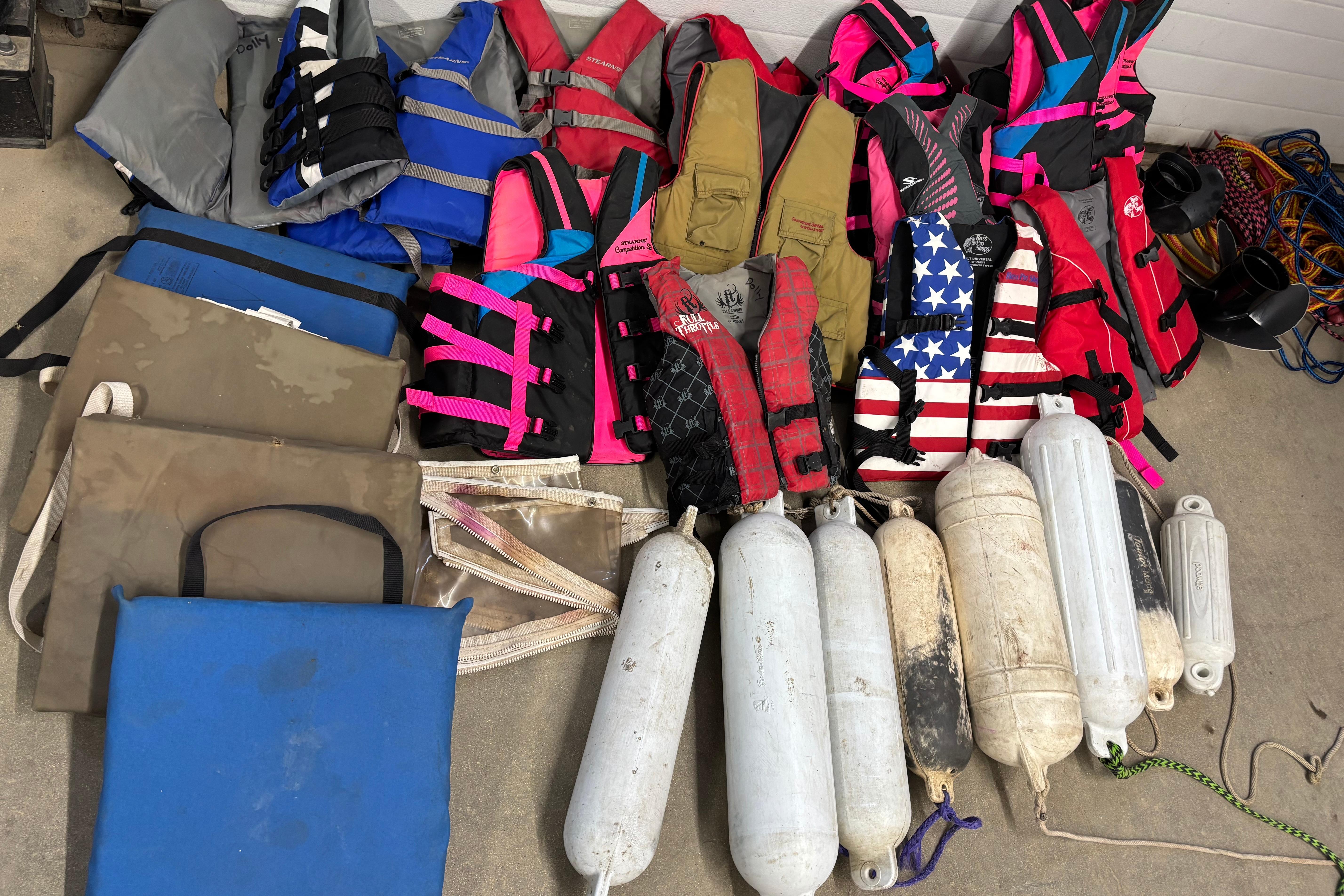 Assorted life jackets and boat fenders on concrete, suitable for Larson SEi 200 Cuddy I/O.