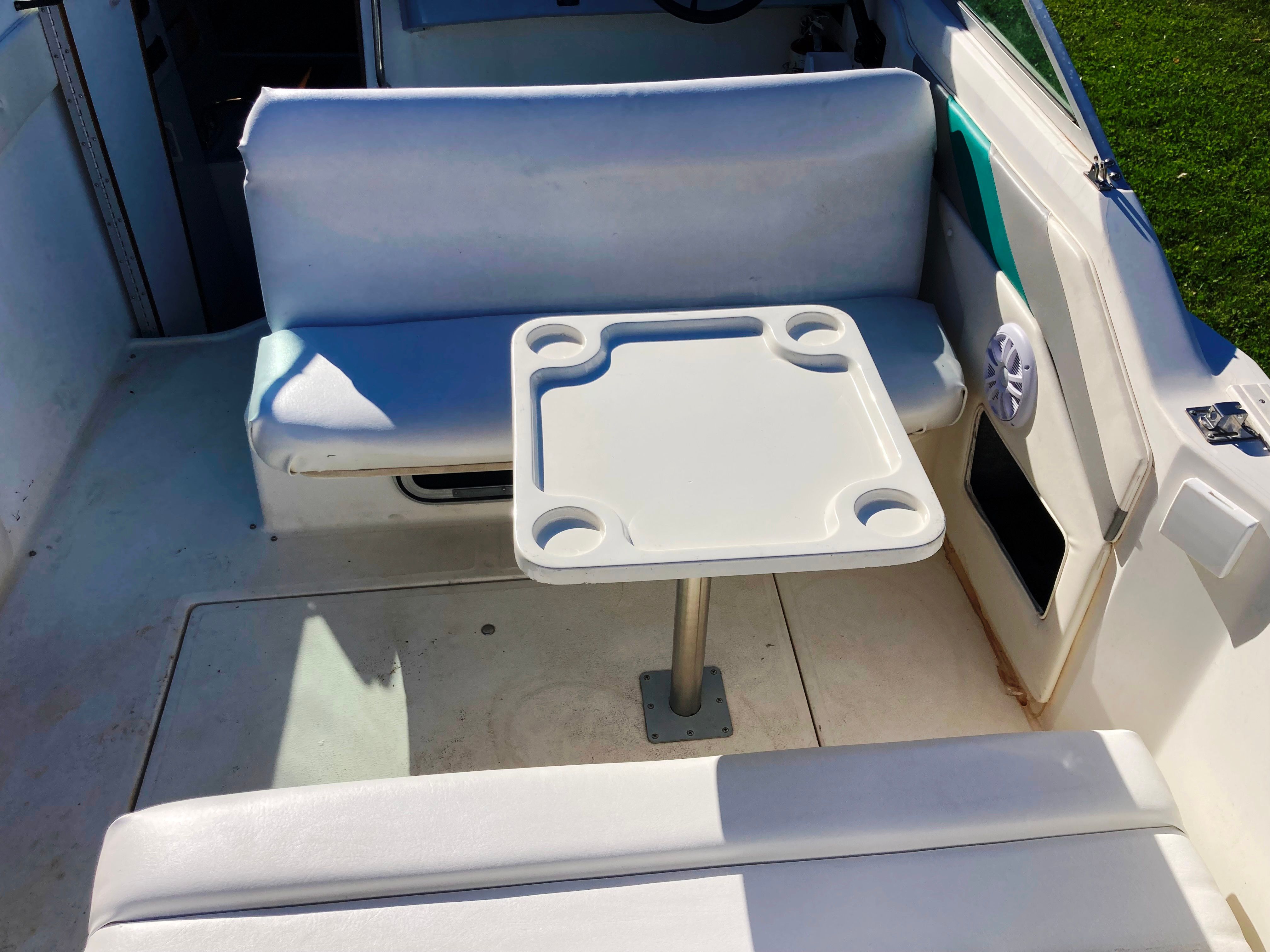 The image shows the seating area of a 1991 Sea Ray 220 Sundancer with a small table.