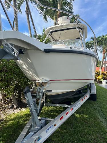 2011 Boston Whaler 235 Conquest boat on trailer, surrounded by palm trees.
