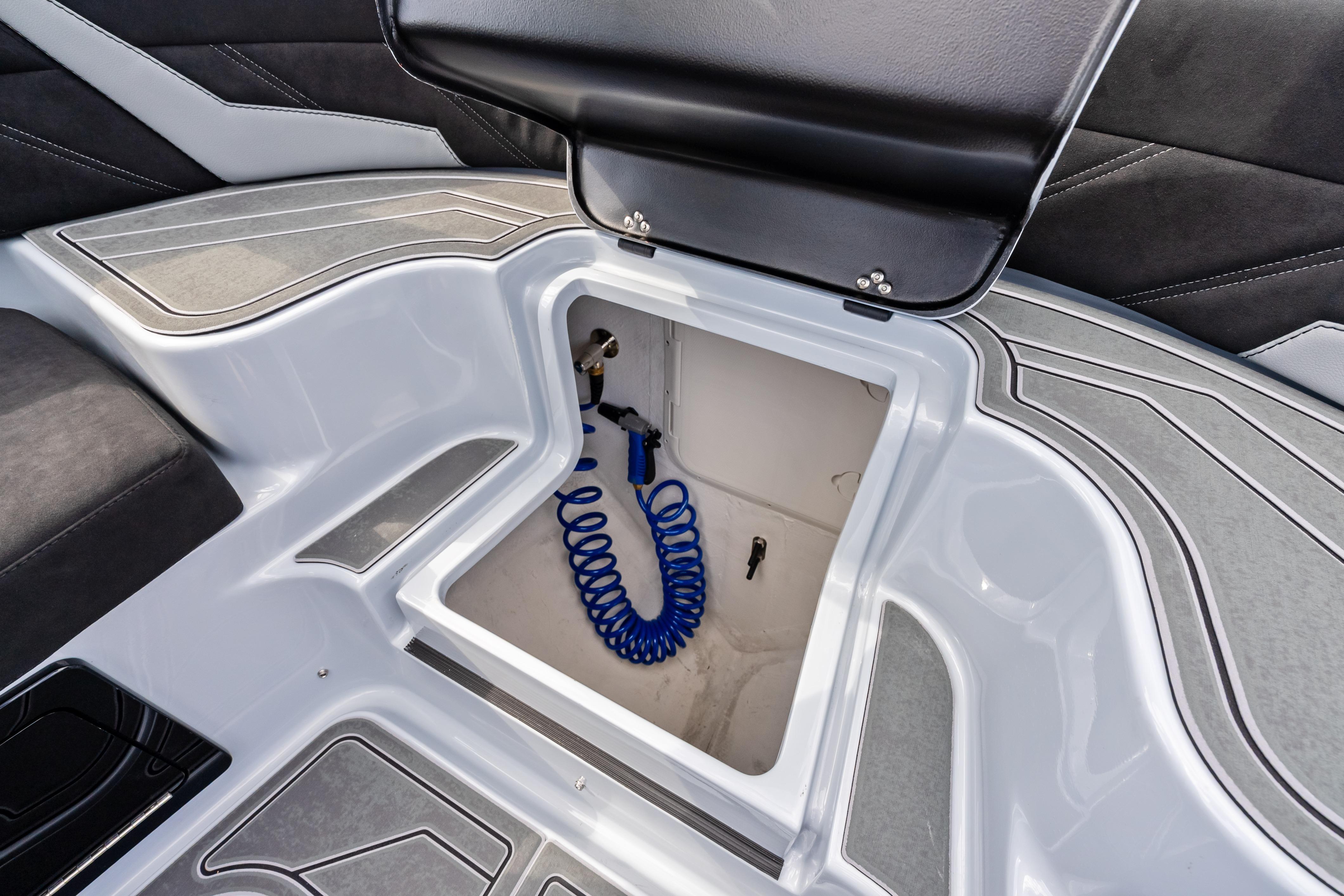 Open storage compartment in 2027 Mystic Powerboats M4200, featuring a coiled blue hose.
