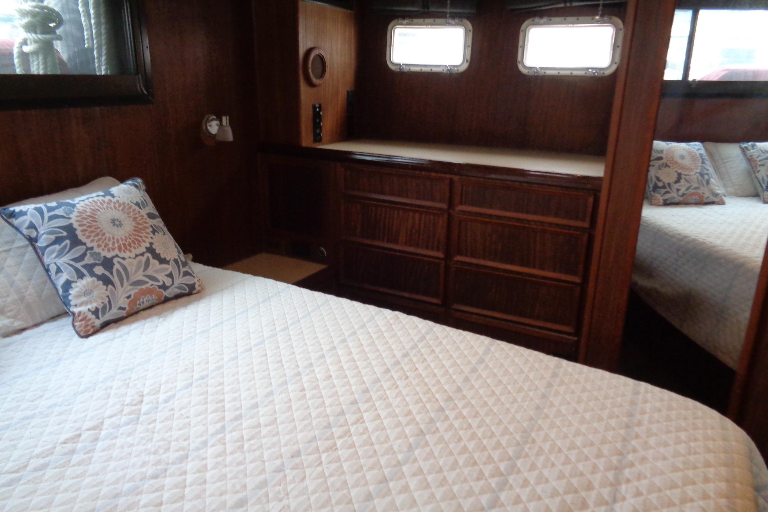 Interior of 1981 Hatteras 48 Cockpit Motor Yacht with cozy bedroom and wooden cabinetry.