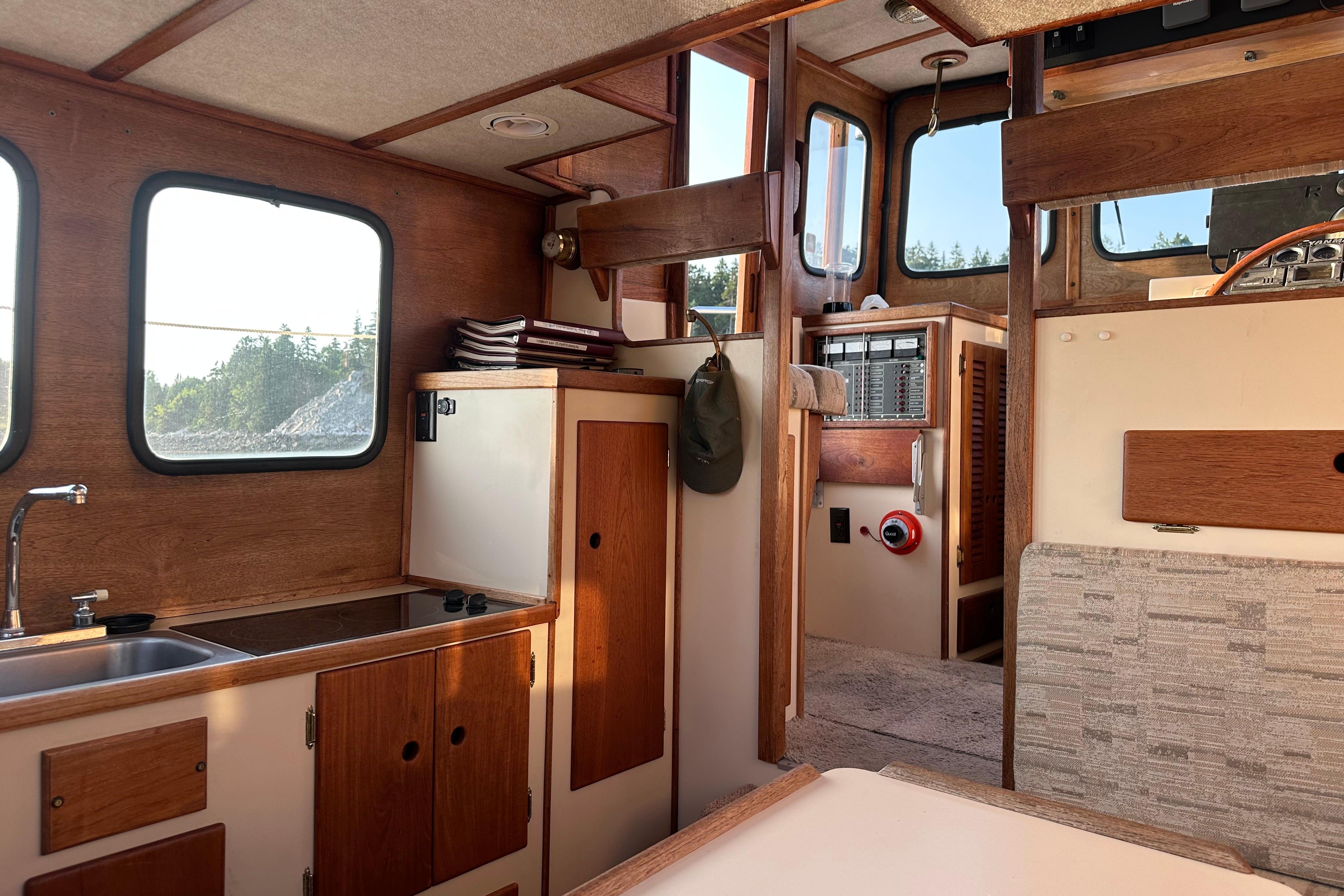 Interior of a 1985 Nordic Tug 26, featuring wood paneling and compact kitchen area.