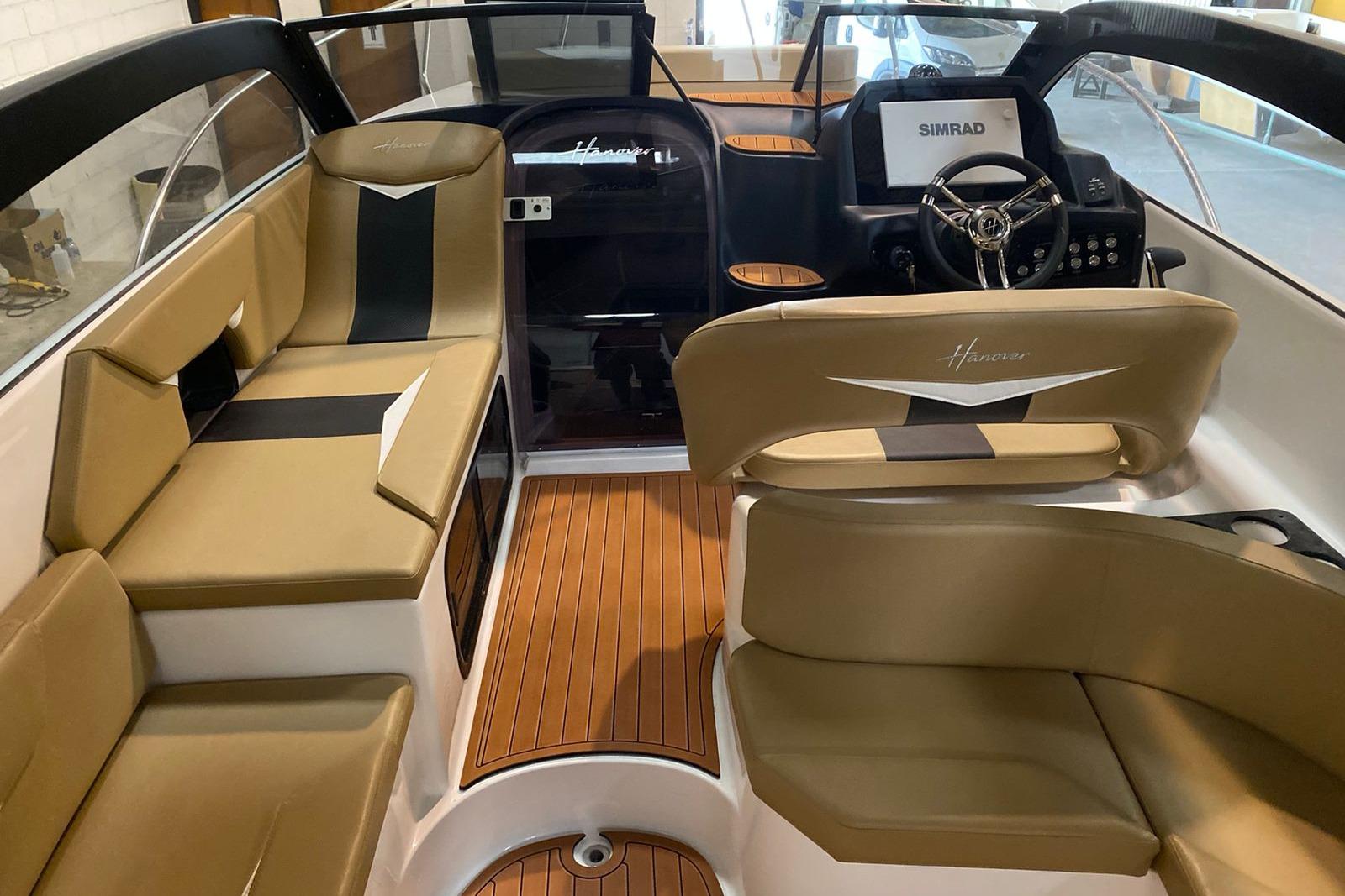 Interior of a 2026 Hanover 305 boat with tan seating and wood flooring.