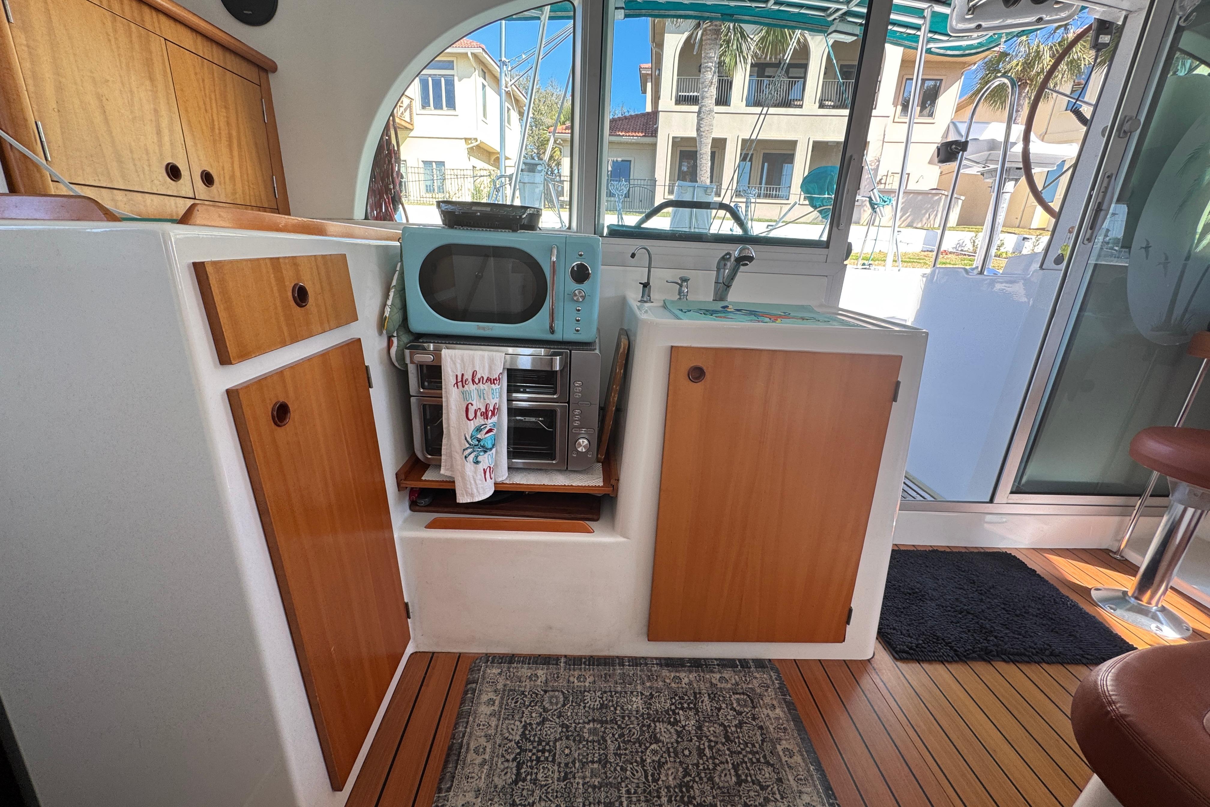 Interior of 2000 Lagoon 380 catamaran with kitchenette, featuring wood cabinets and retro appliances.