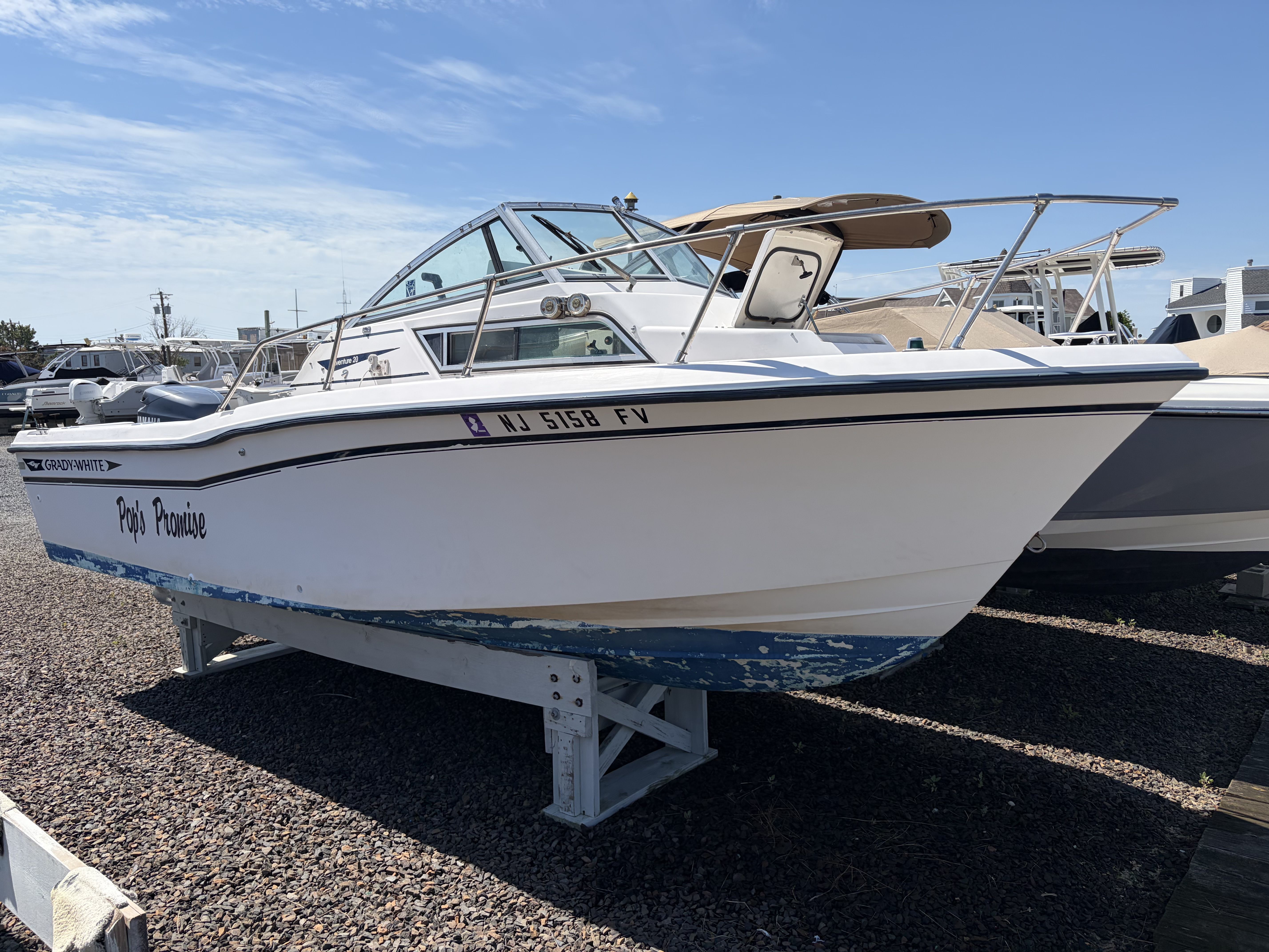 A 1993 Grady-White Adventure 208 boat is on a stand on gravel.