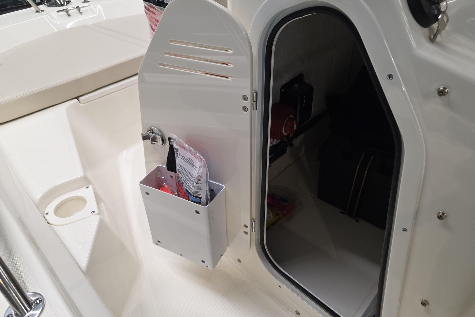 2026 Boston Whaler 150 Montauk storage compartment with open door and interior view.