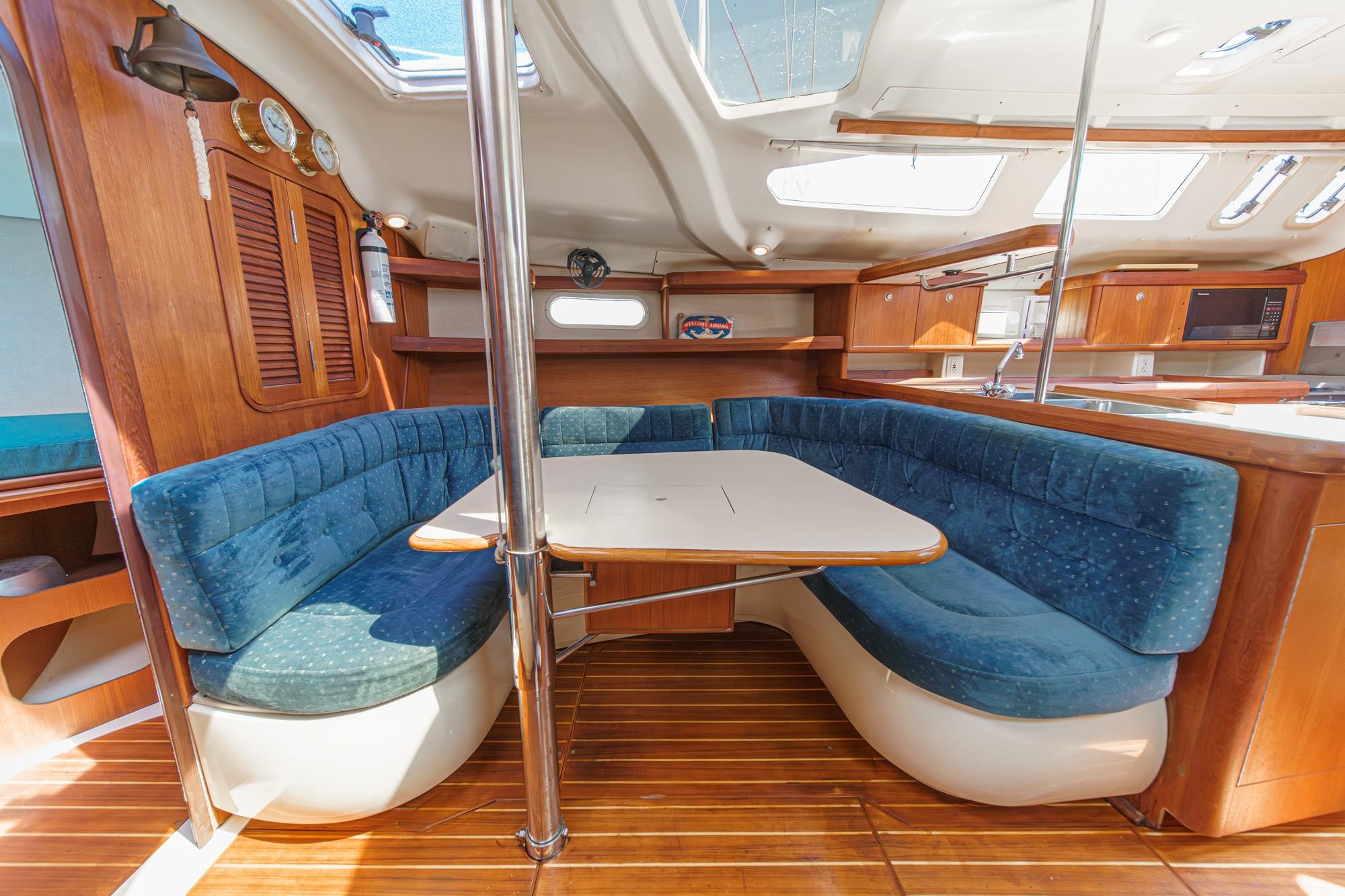 Interior of a 1996 Hunter 376 sailboat with blue cushioned seating and wooden finishes.