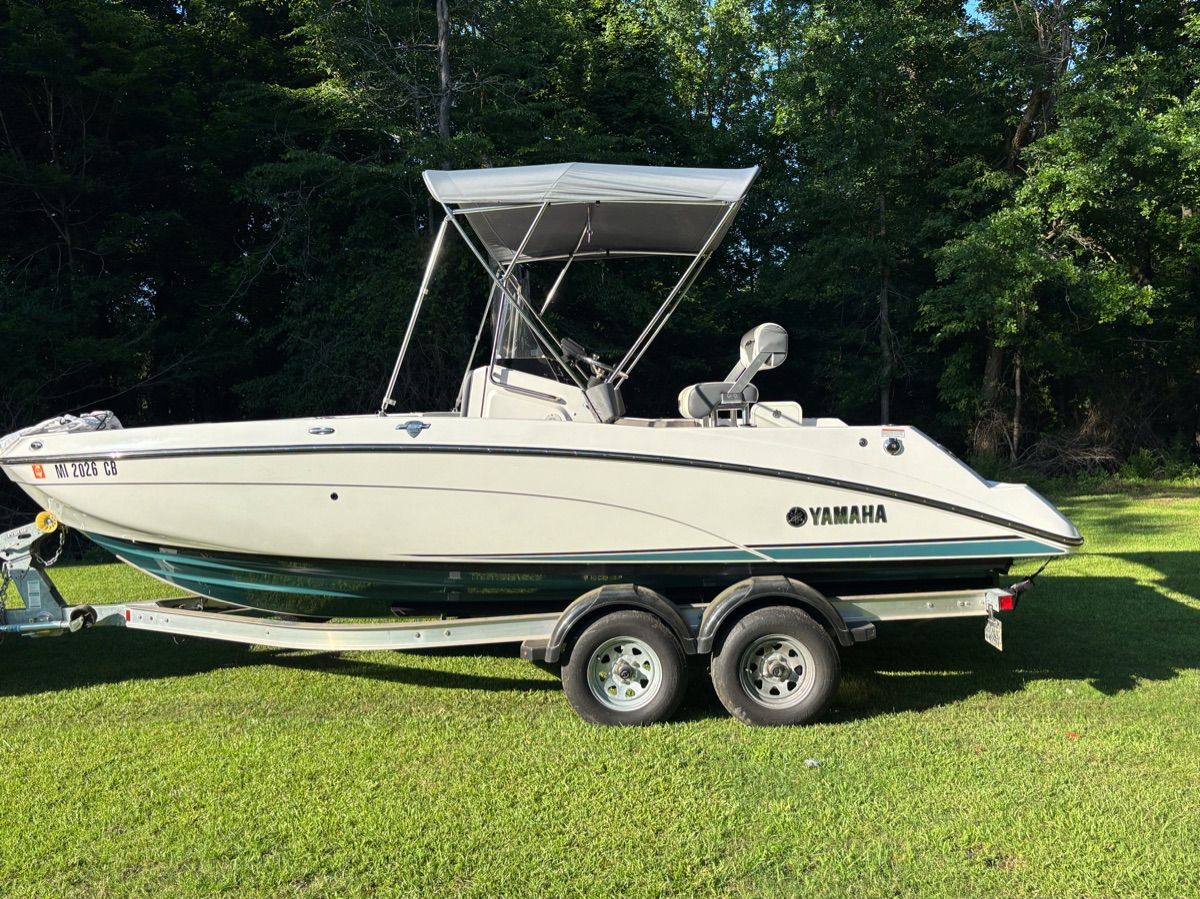 2020 Yamaha 210 FSH Deluxe boat on trailer in grassy area.