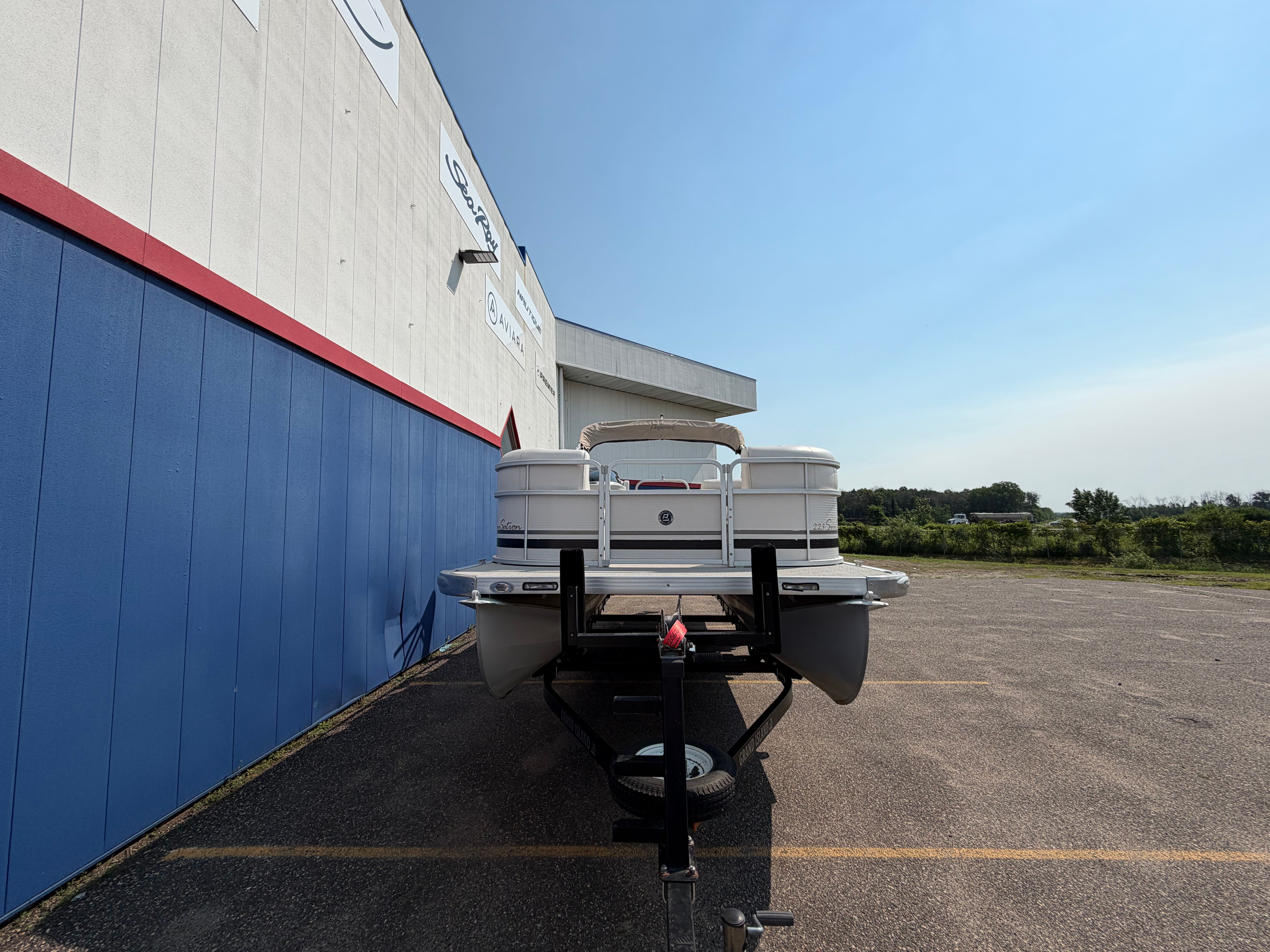 A 2007 Premier 225 Sunsation pontoon boat on a trailer in front of a building.