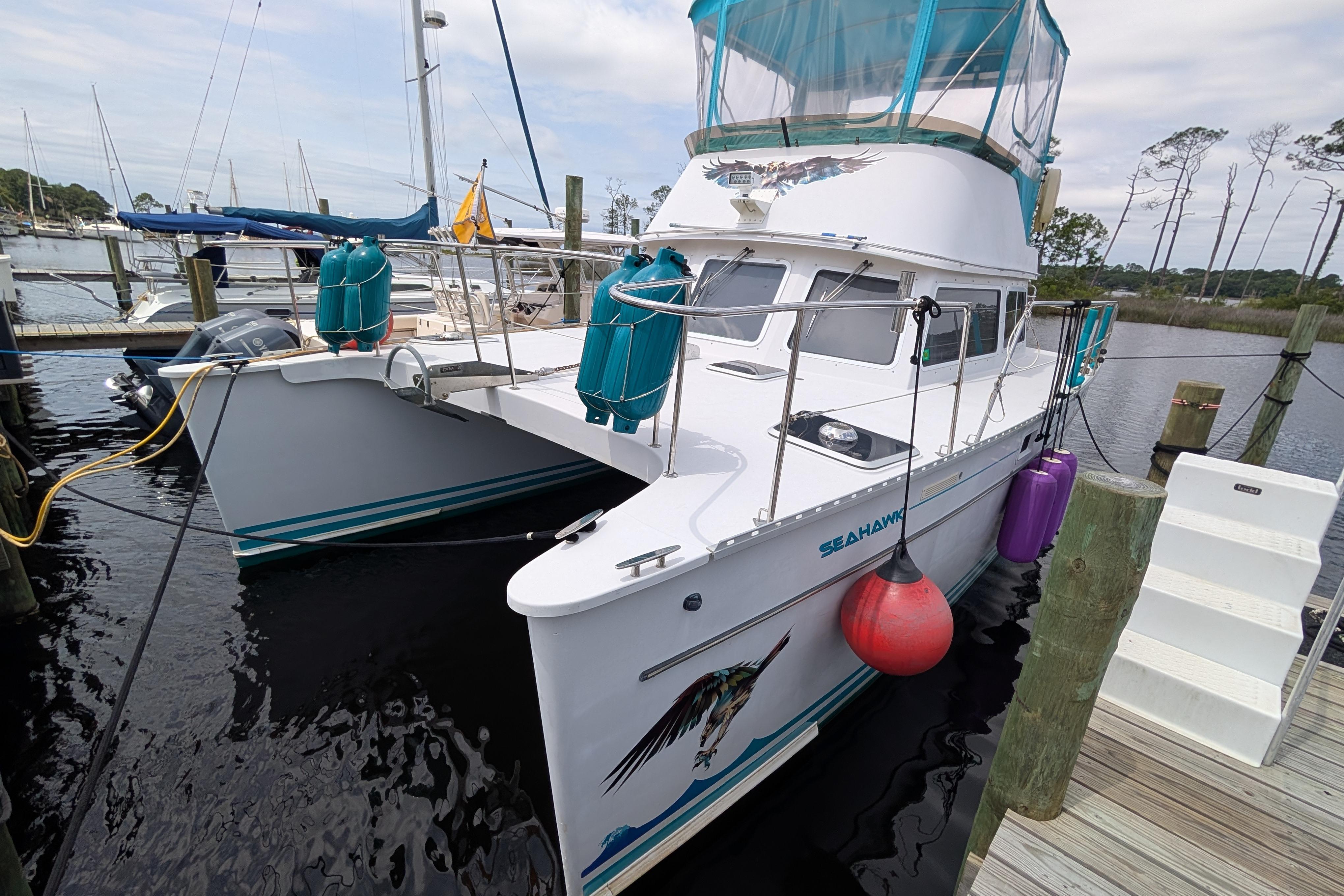 2004 PDQ 34 Powercat docked, featuring vibrant fenders and a spacious deck.