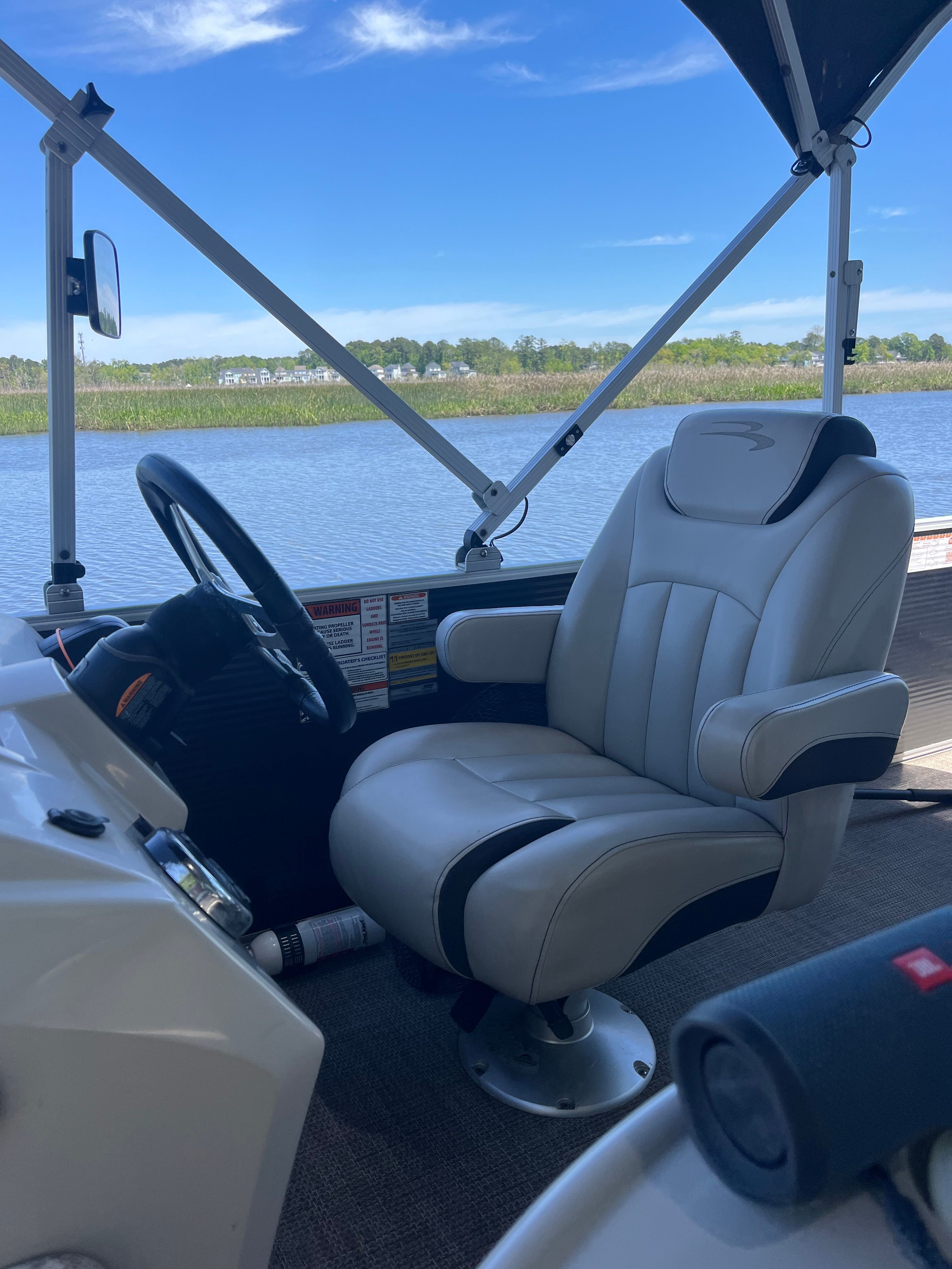 A sleek captain's chair on a boat overlooking calm water and blue skies.