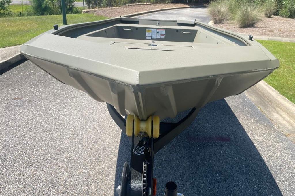 2026 Tracker Grizzly 1648 Utility boat on trailer, parked on asphalt near grass.