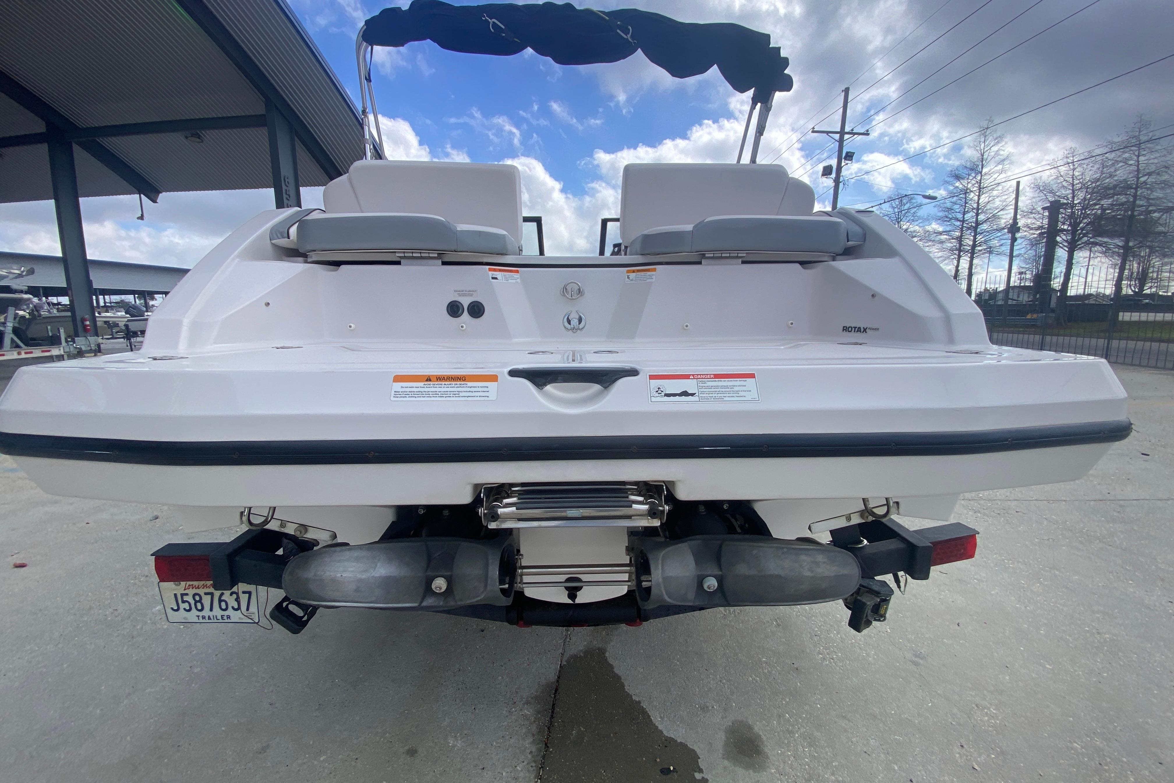 Rear view of a 2018 Scarab 215 G boat with dual engines and trailer.